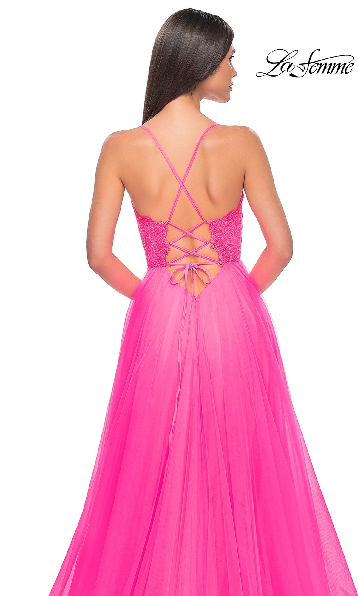Woman wearing the La Femme Lace-Bodice Long A-Line Prom Dress 32306 in bright pink, featuring a lace-up back, thin straps, and a flowing tulle skirt, as she faces away from the camera.