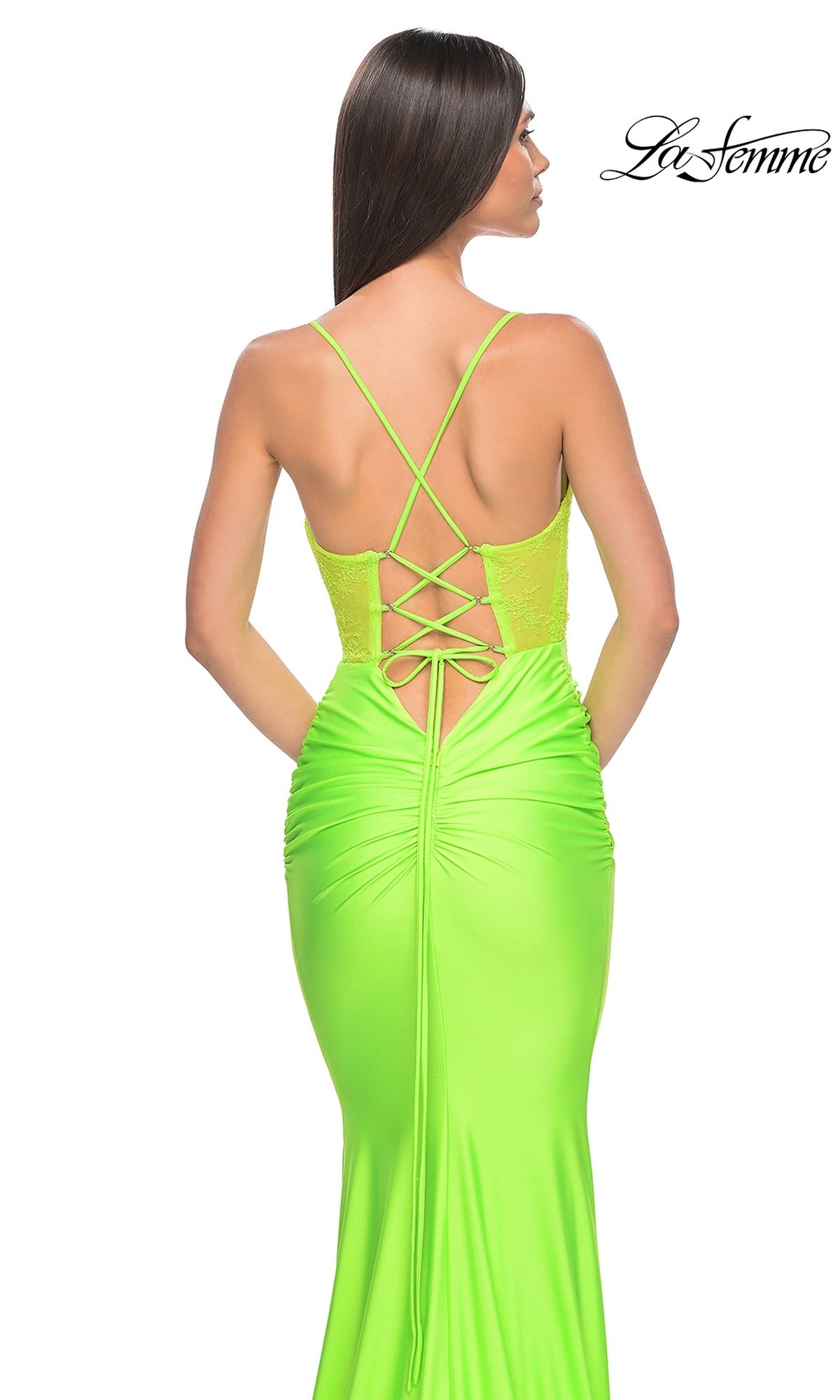 A woman is seen from behind in the La Femme Sheer-Bodice Long Prom Dress 32322, a bright neon green gown featuring thin crisscross straps and a lace-up back.