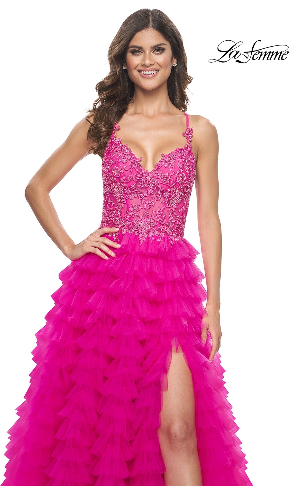 A woman models the La Femme Hot Pink Long Ruffled Prom Dress 32334, featuring a ruffled A-line skirt, embroidered lace bodice with spaghetti straps, and a high slit, against a white background.