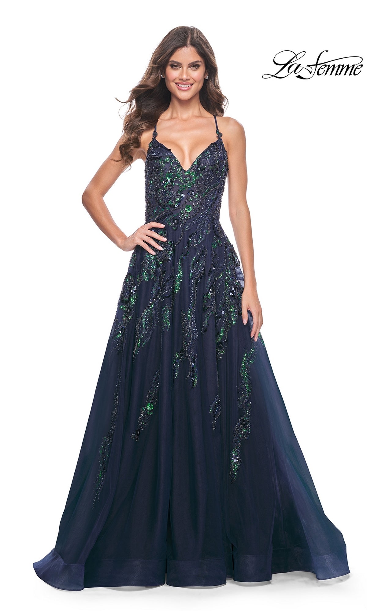 A woman stands smiling in the La Femme Long A-Line Sequin-Print Prom Dress 32346, a navy blue floor-length gown with green embellishments. The La Femme logo is shown in the top right corner.