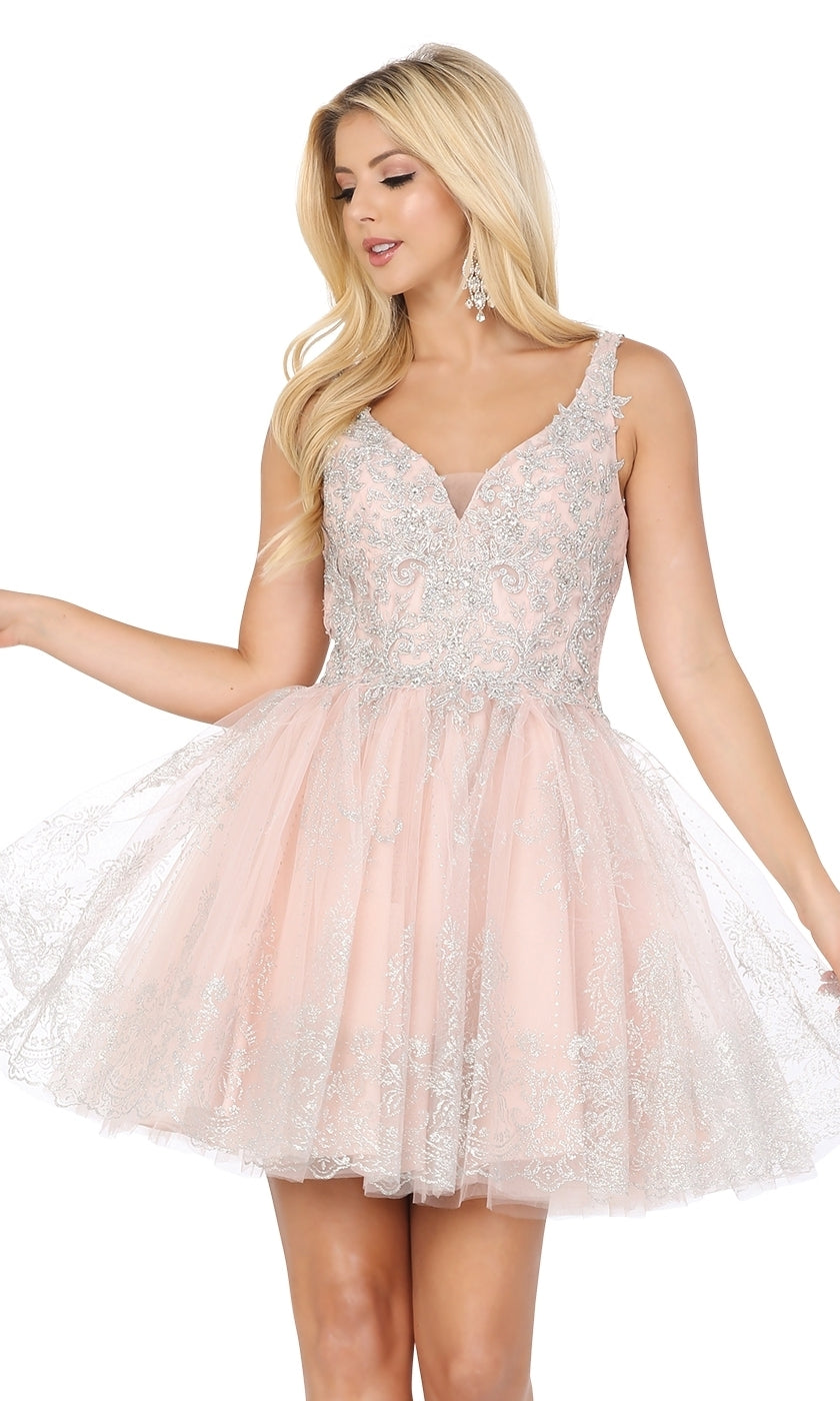 A woman models the Silver-Beaded Short Babydoll Hoco Dress 3237, a light pink sleeveless dress with silver embroidery, posing with one arm slightly raised.