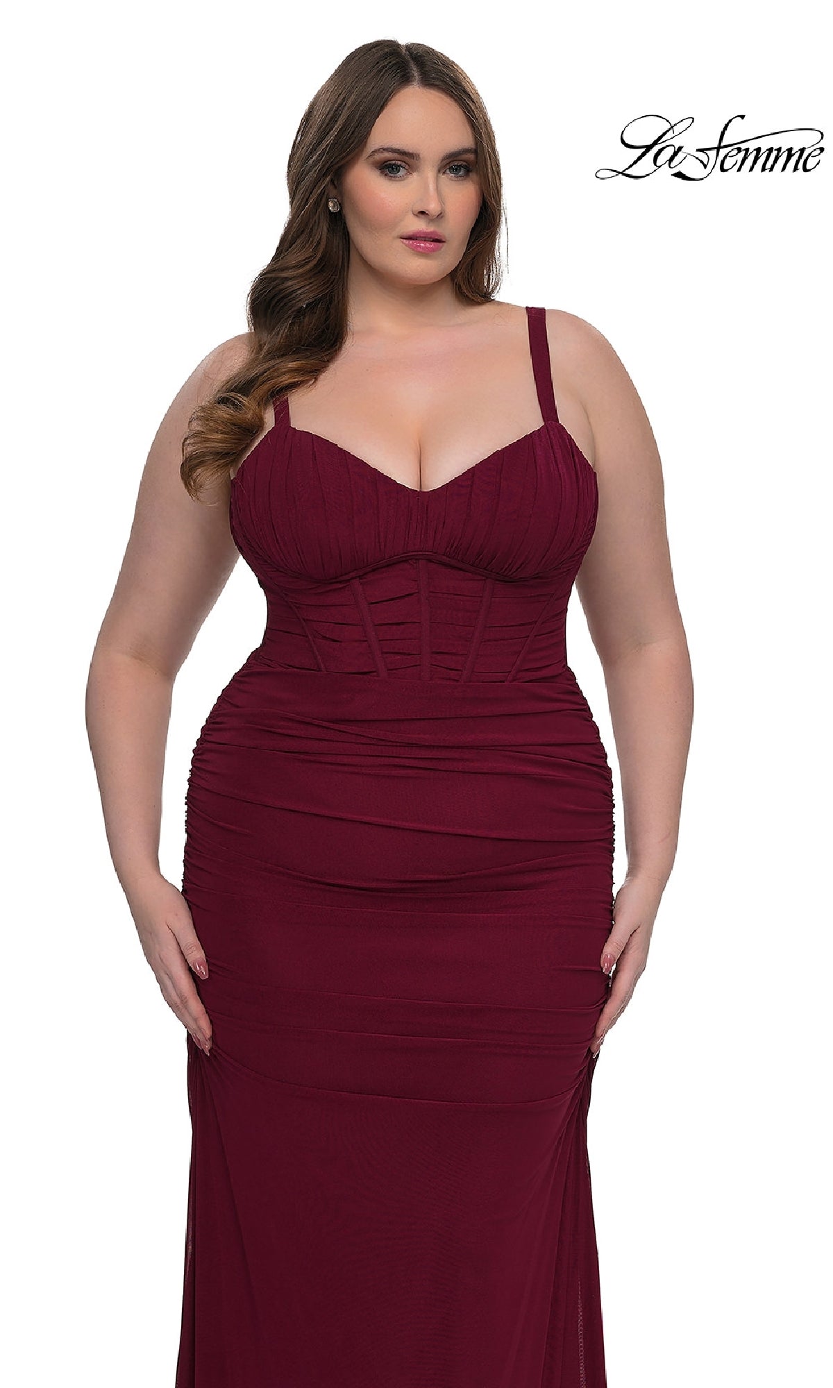 A woman wears the Plus-Size Sexy Long Prom Dress La Femme 32402, a fitted sleeveless burgundy gown with ruched detailing, wide straps, and a corset-style bodice. She stands against a plain white background with the