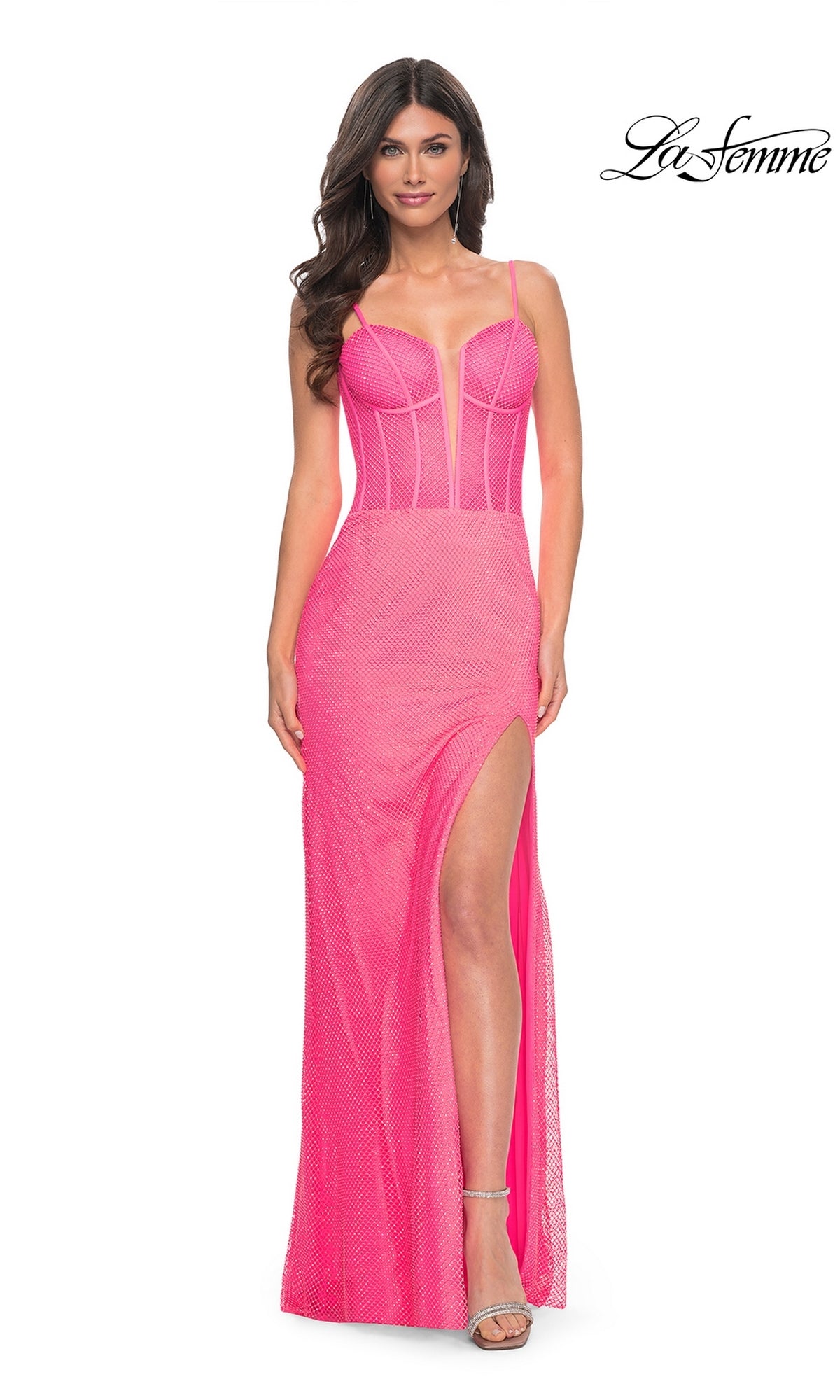 A woman in the Hot Pink Long Corset Prom Dress: La Femme 32426, featuring a fitted bodice, sheer panels, and a high slit, stands against a white background with the