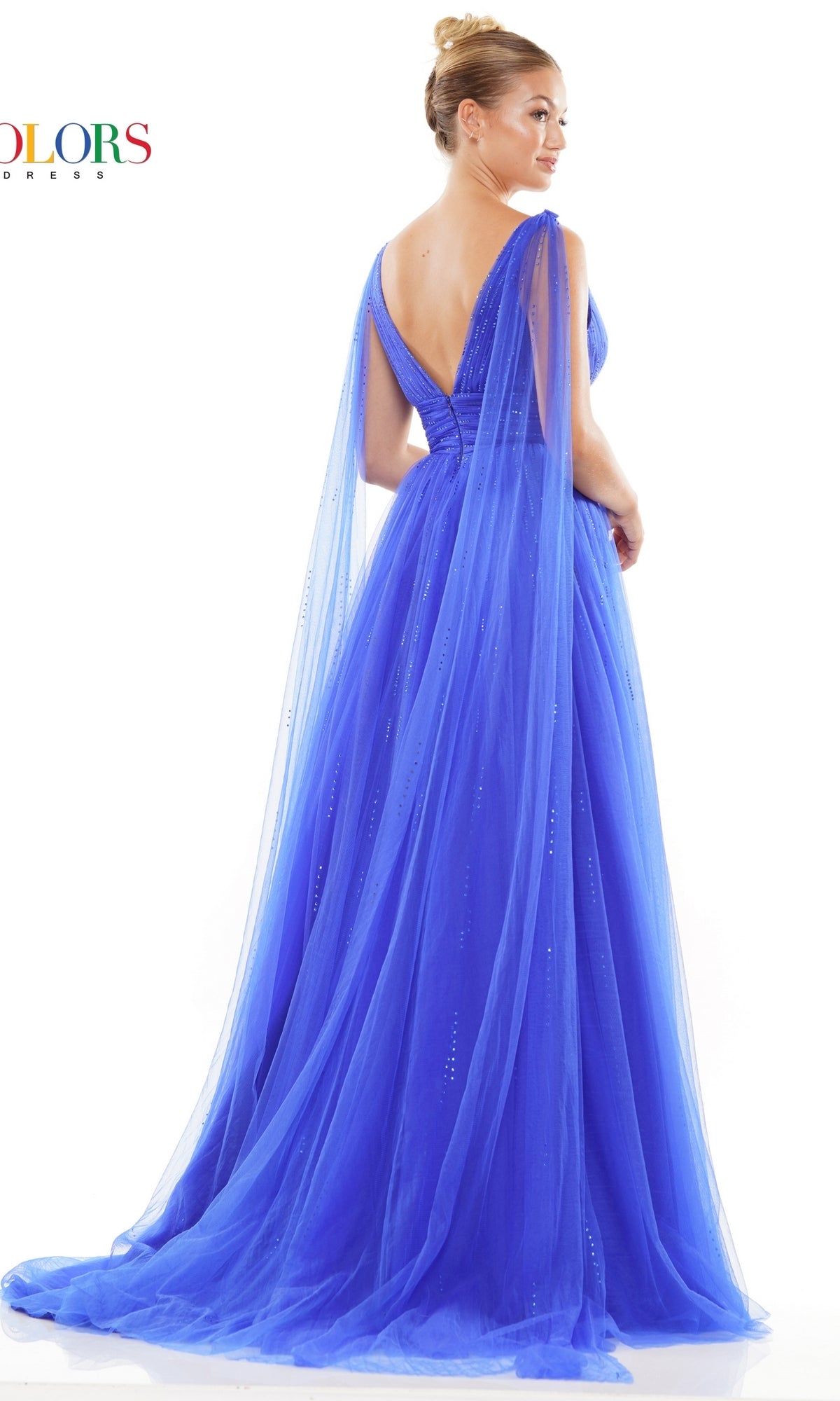 A woman stands against a white background in the Classic Long Prom Ball Gown: Colors Dress 3242, a royal blue floor-length evening gown featuring a v-neck, deep V-back, and sheer flowing cape sleeves.