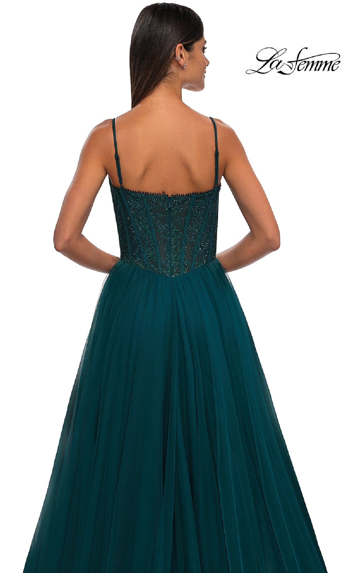 Woman in a dark teal, floor-length La Femme 32594 prom ball gown with thin straps and beaded bodice, featuring a lace corset back, standing with her back to the camera.