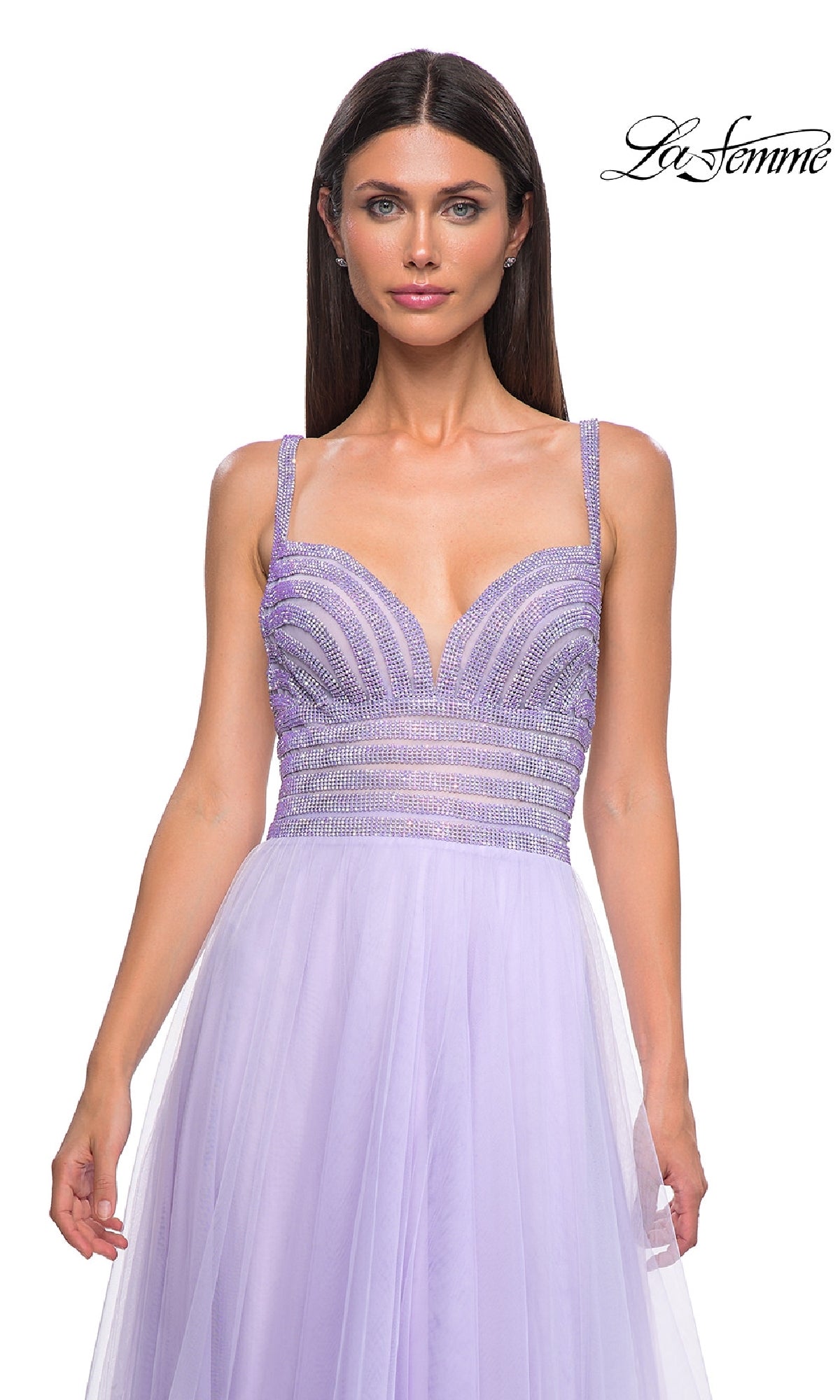 A woman in the La Femme 32714 Rhinestone-Bodice Prom Ball Gown—a lavender, long tulle A-line dress with a beaded bodice—stands before a white background featuring the “La Femme” logo.