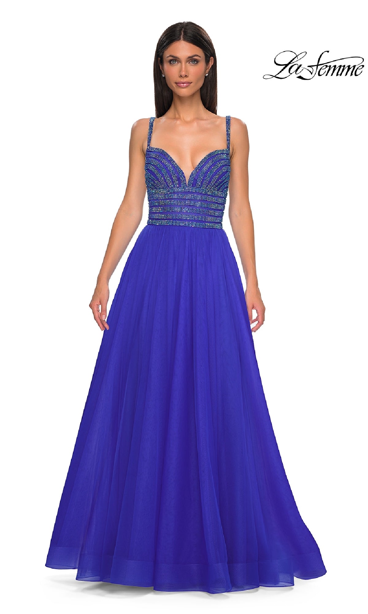 A woman models the La Femme 32714 prom ball gown—a royal blue, A-line dress with thin straps and a sparkling rhinestone-bodice—against a white background.