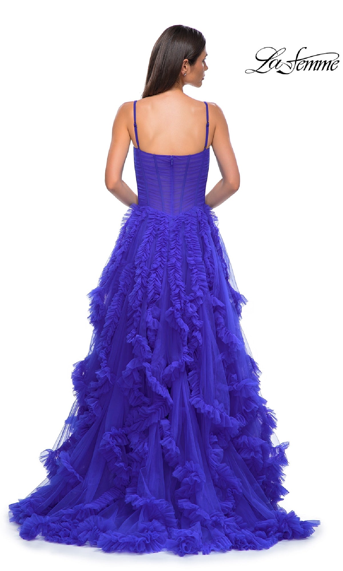 A woman, seen from behind, wears the Ruffled-Tulle Long Prom Ball Gown: La Femme 32719—a royal blue dress with spaghetti straps and a layered tulle skirt. The