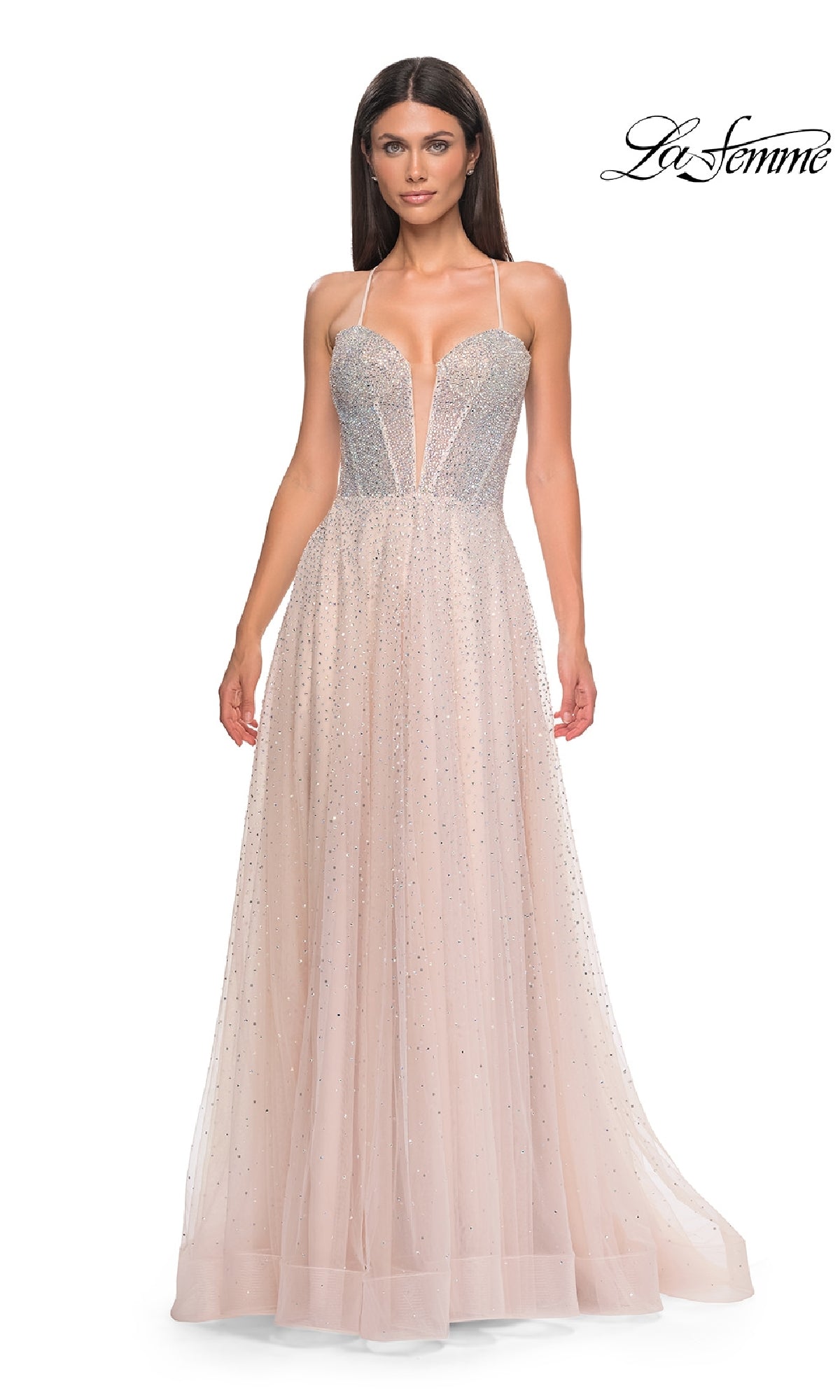 A woman wears the Lace-Up Beaded Long Prom Ball Gown, La Femme 32725—a sleeveless, light pink dress with a deep V-neck and sparkling embellishments—standing against a white background.