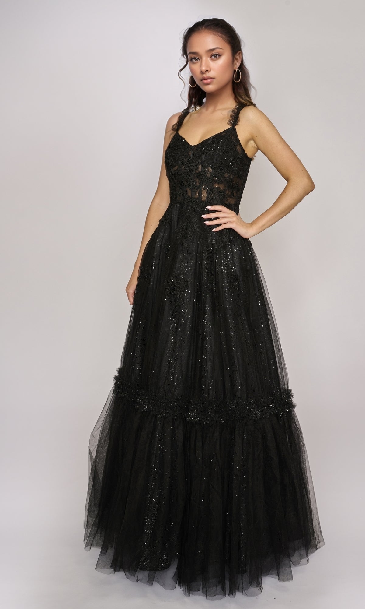A woman wears the Nina Canacci 3272 long formal dress, showcasing a sleeveless lace-fitted bodice and flared tulle skirt against a plain light background.
