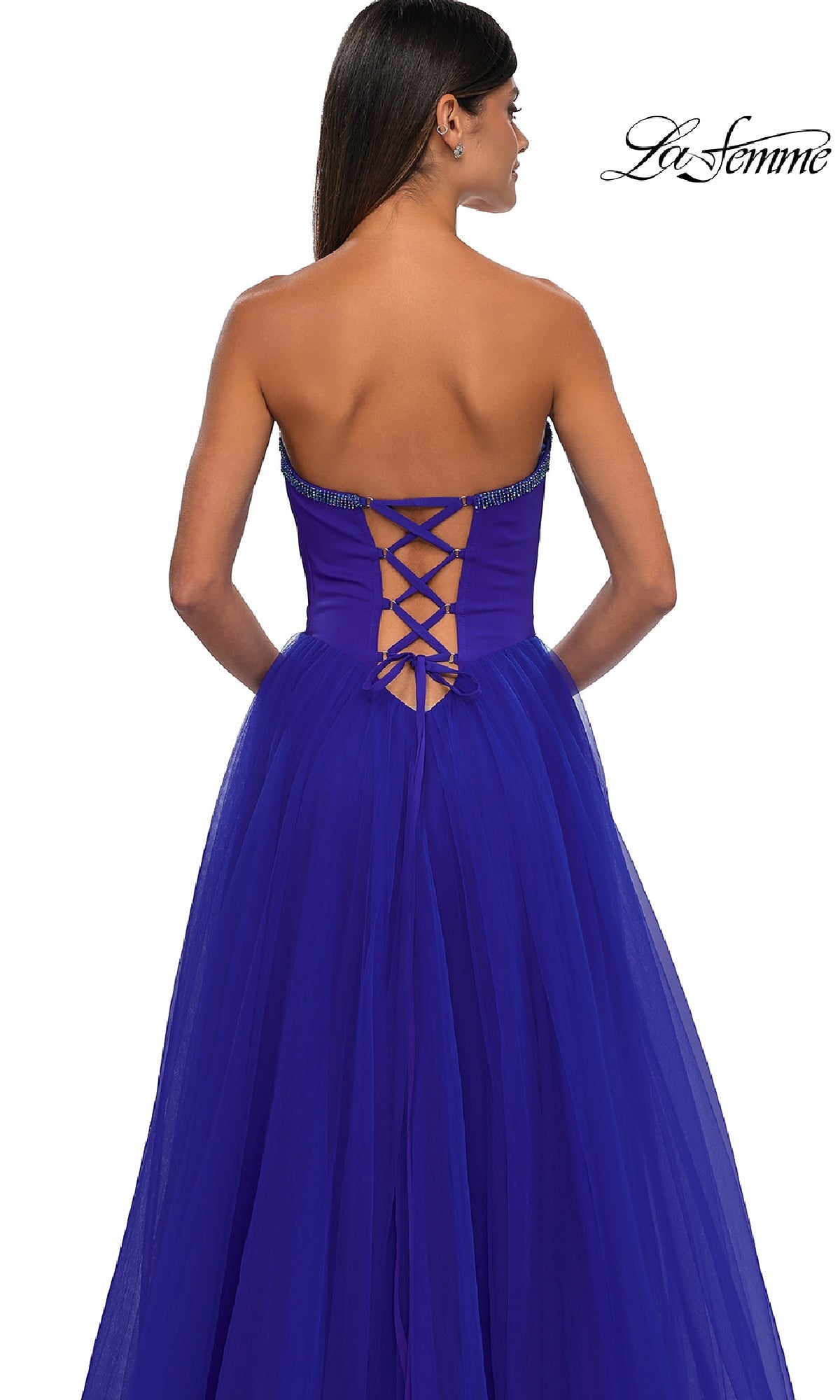 A woman models the La Femme 32731 strapless long prom ball gown in royal blue, shown from behind to highlight the sweetheart neckline, floor-length skirt, and elegant lace-up back detail.