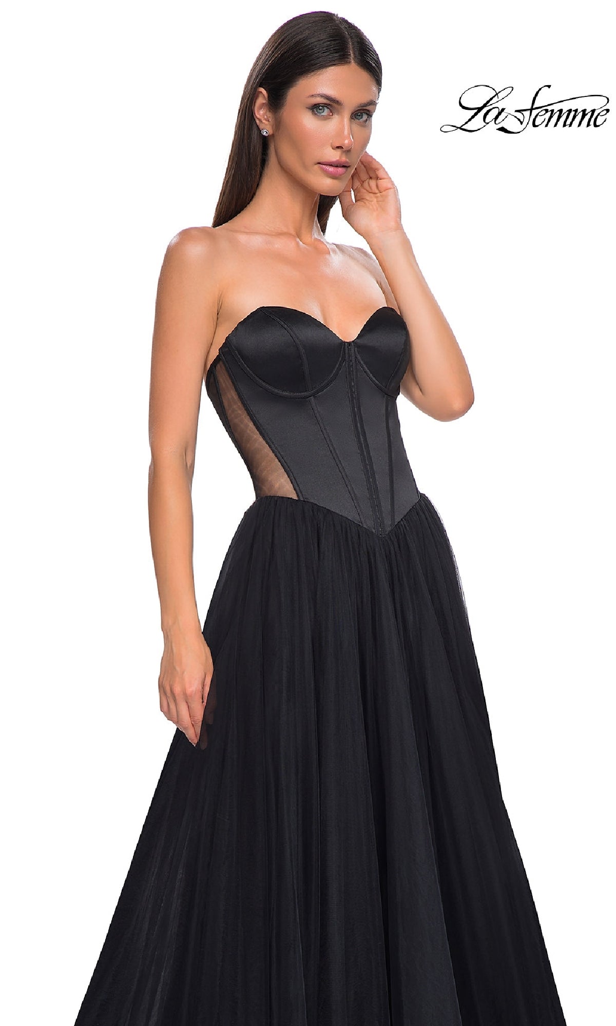 A woman models the La Femme 32771 Black Strapless Long Prom Dress with a fitted corset bodice and tulle skirt, standing against a white background. The