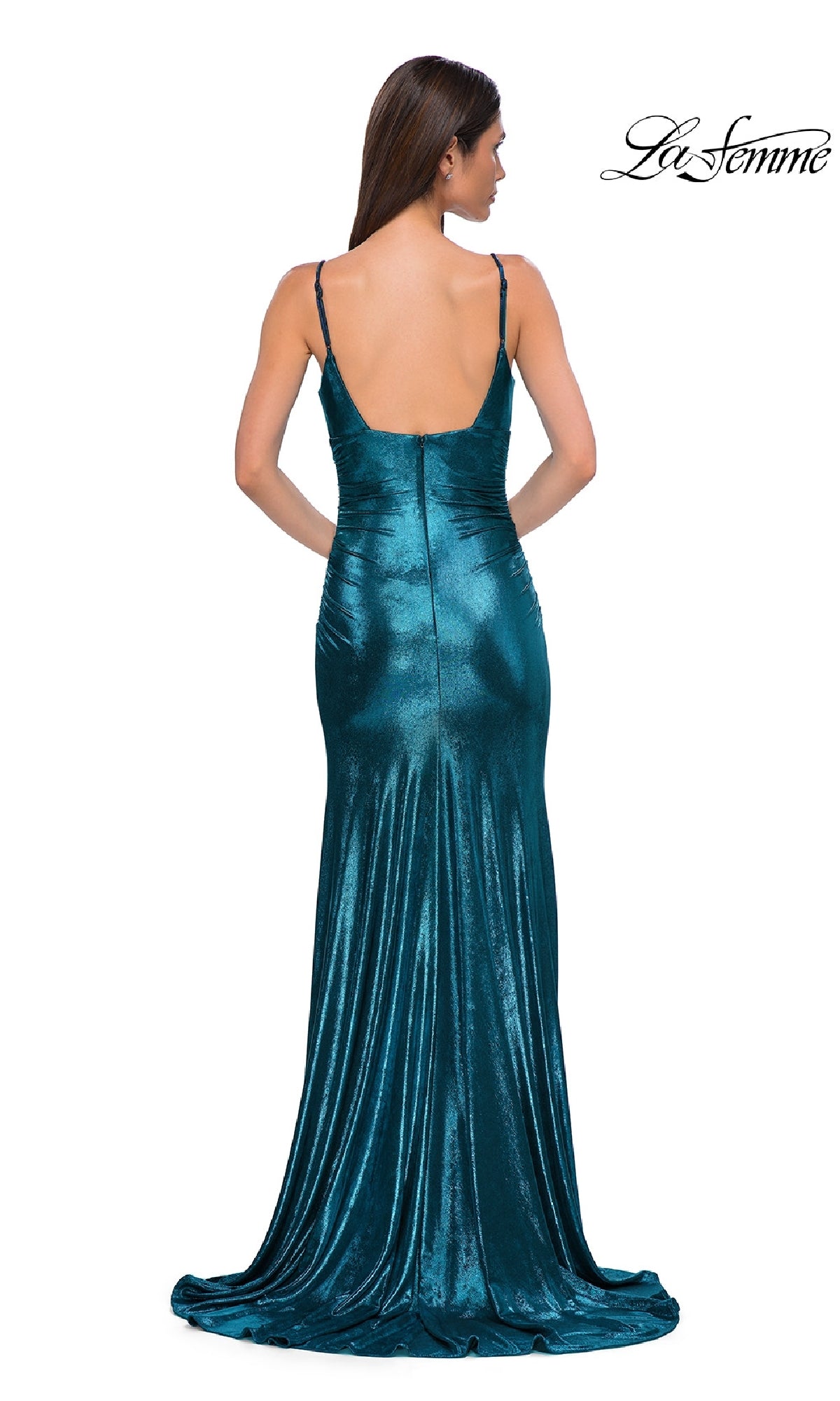 A woman stands facing away from the camera, wearing the La Femme 32812 V-Neck Long Metallic Prom Dress—a teal, floor-length gown with thin straps and a low back.