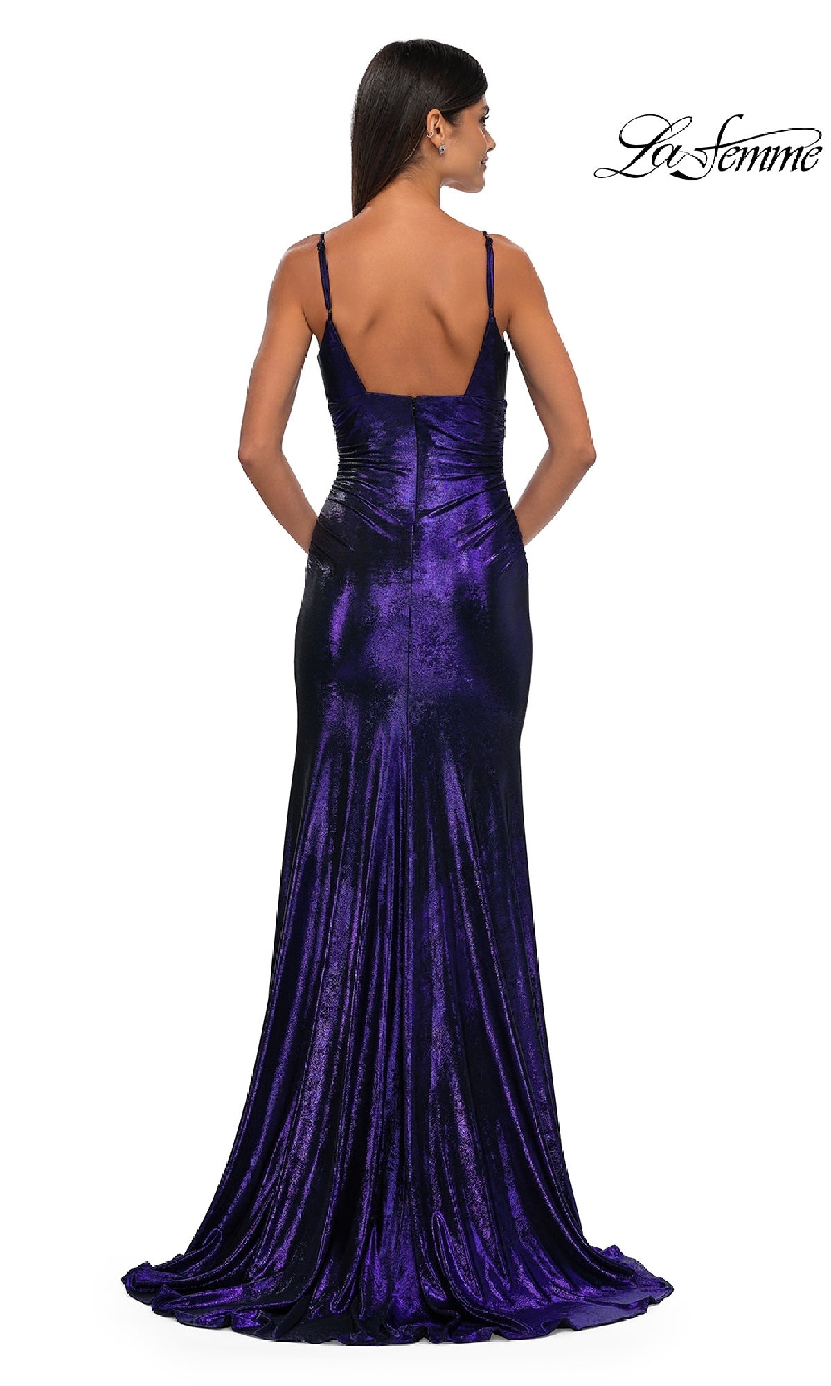 A woman faces away from the camera in the La Femme 32812 V-Neck Long Metallic Prom Dress, a fitted, floor-length designer gown with thin straps, deep purple velvet fabric, and a slight train.