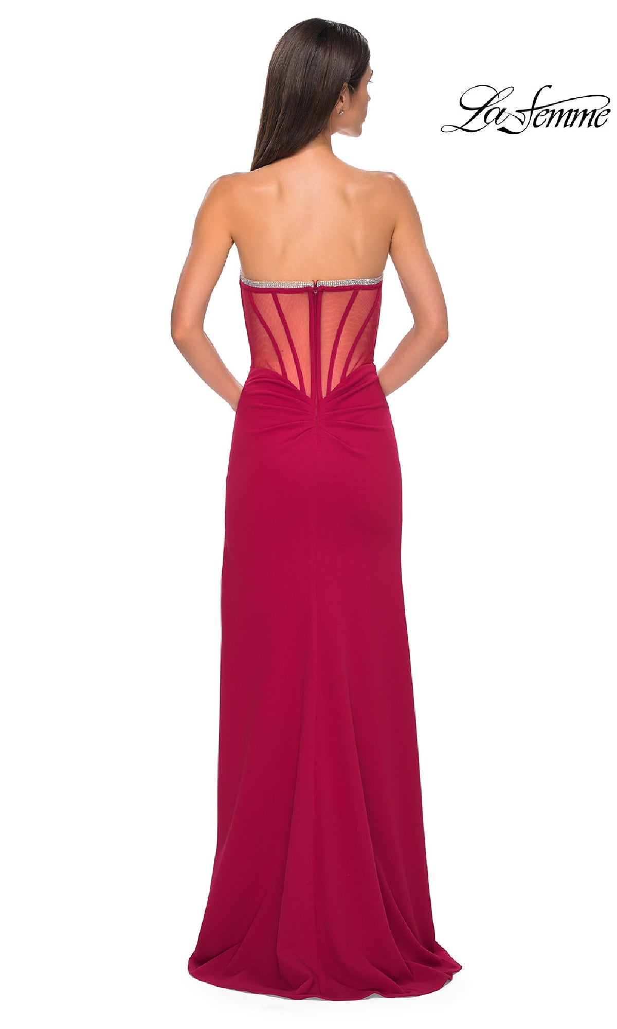 A woman faces away from the camera in the La Femme 32825 Bead-Trimmed Strapless Prom Gown—a floor-length magenta dress with a fitted silhouette and sheer back panel details.
