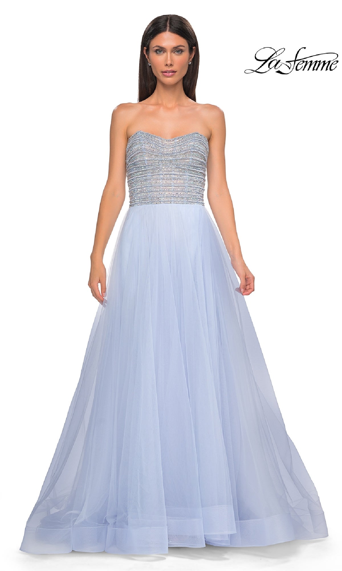 A woman models the Strapless Long Prom Ball Gown: La Femme 32875, featuring a fitted, beaded bodice and flowing light blue tulle skirt, against a plain white background.