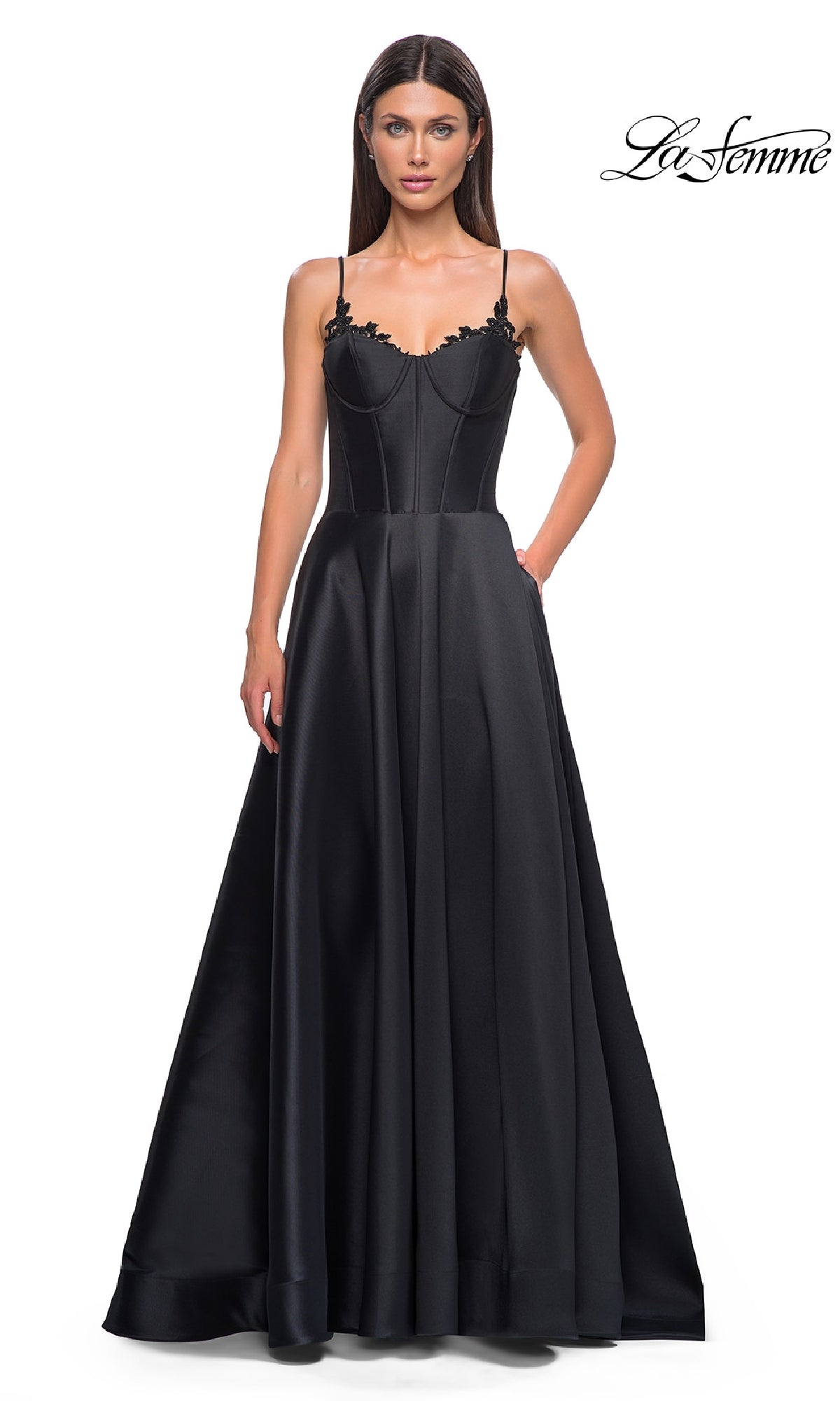 A woman models the La Femme 32878 Lace-Up Long Mikado Prom Dress, a black satin floor-length gown with thin straps and a fitted bodice, standing against a white background with the La Femme logo in the top right corner.