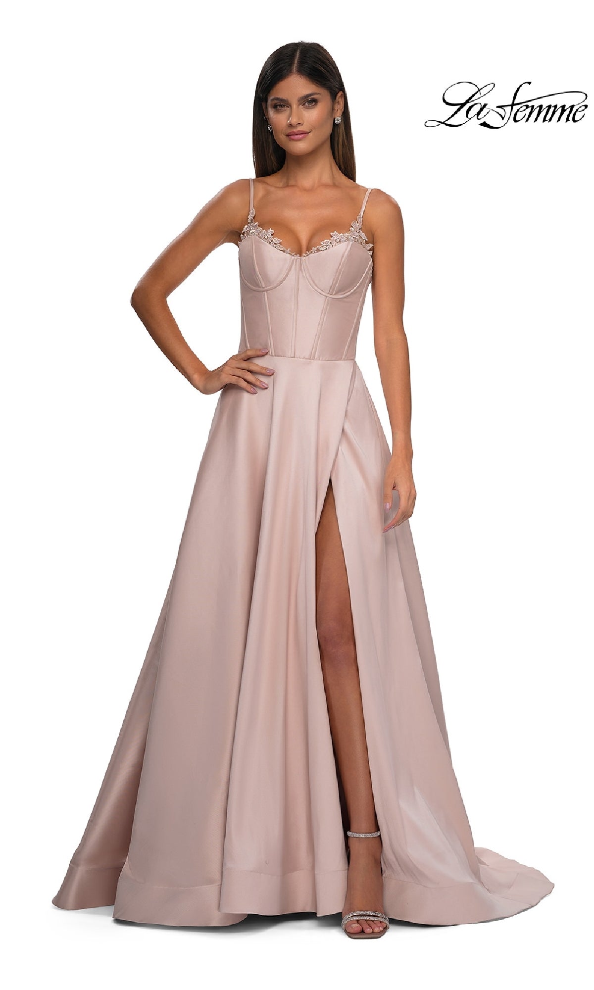 A woman wears the Lace-Up Long Mikado Prom Dress (La Femme 32878) in blush pink, featuring a floor-length A-line silhouette, fitted bodice, thin straps, and high slit, standing against a plain white background.