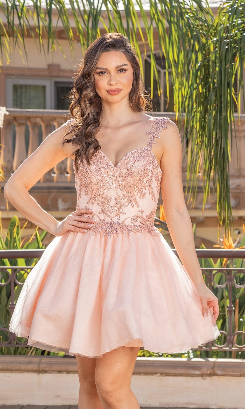 A woman stands outdoors in front of greenery and a building, wearing the Babydoll Glitter-Embroidery Short Prom Dress—a sleeveless, light pink A-line dress with floral and glitter embroidery.