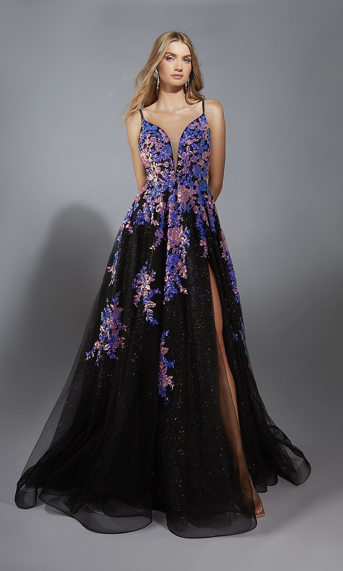 A woman models the A-Line Glitter Prom Dress: Aerie Couture 328, a sleeveless black gown with a deep neckline, purple floral sequin embroidery, and a high slit against a plain gray background.