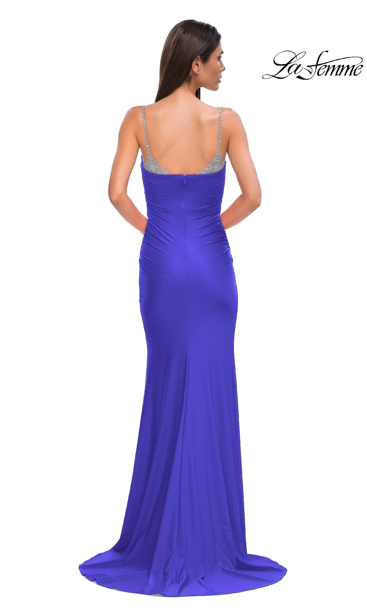 A woman poses with her back to the camera in a royal blue La Femme 32939 Beaded-Neckline Long Prom Dress, featuring thin silver straps and a beaded v-neckline, against a white background.