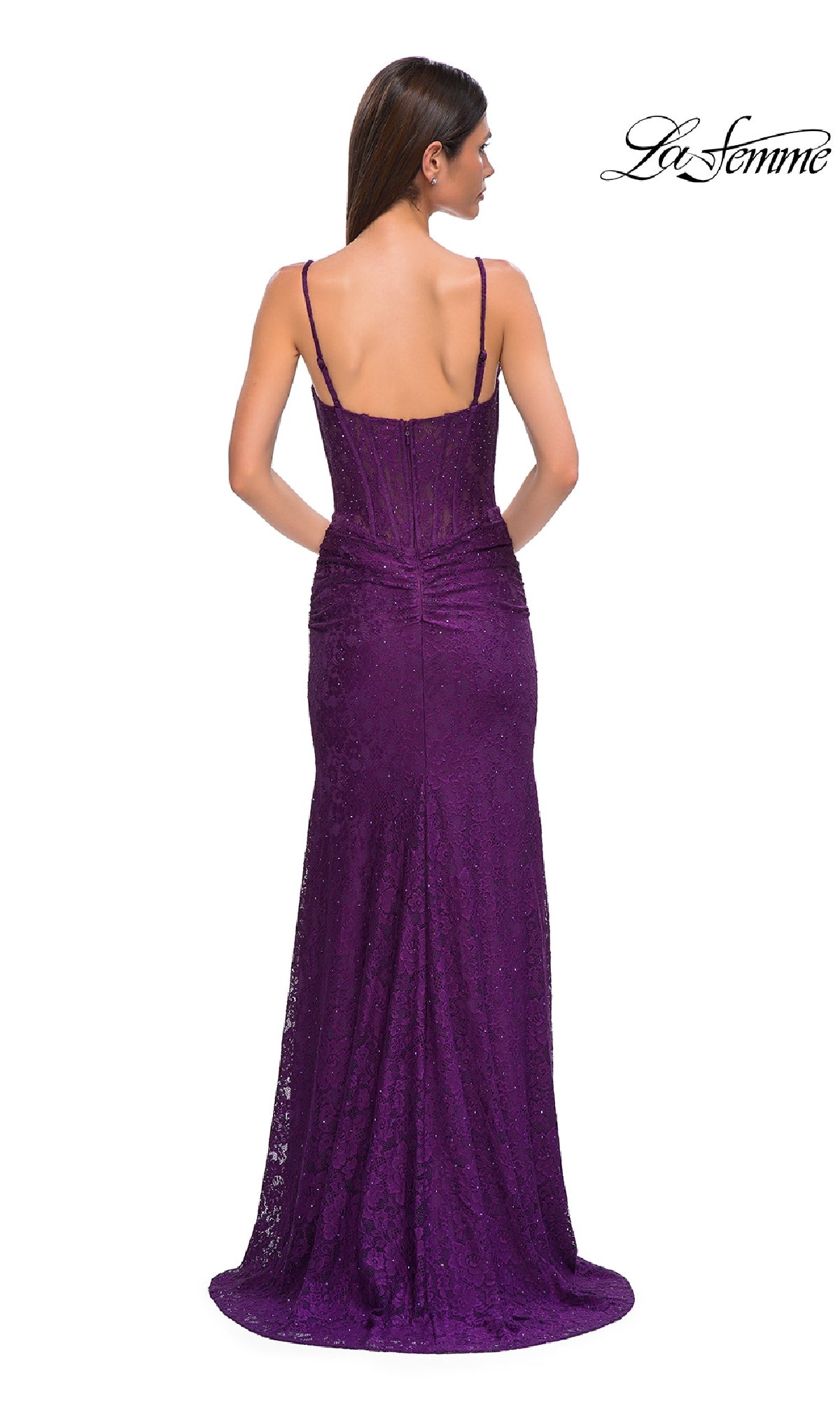 A woman is shown from the back in the La Femme 32947: a floor-length, deep purple sheer-waist beaded prom dress with thin straps, a fitted bodice, and a slight train.