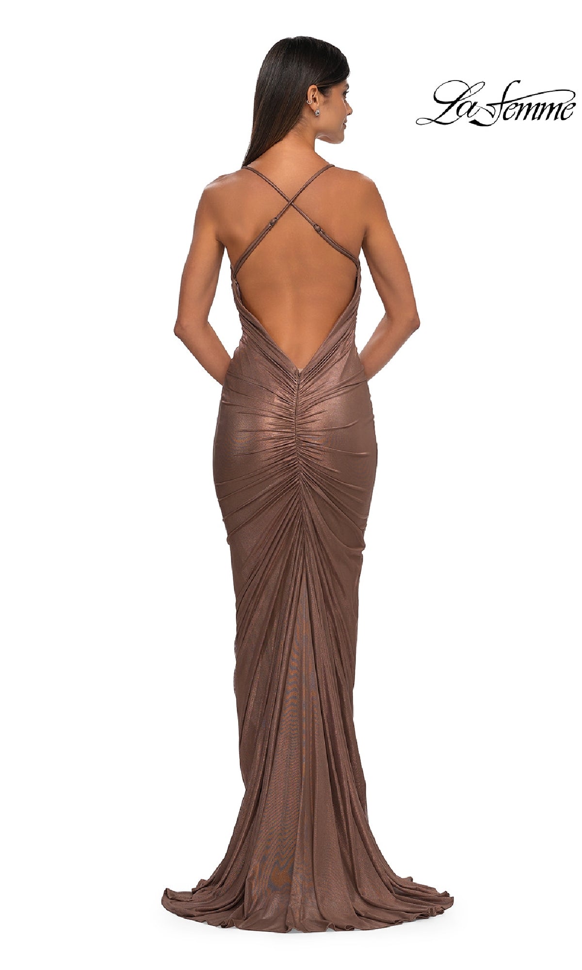 A woman wears the La Femme 32973 Backless Metallic Jersey Prom Dress in brown, featuring a floor-length design, low back, and crisscross straps, standing with her back to the camera. La Femme logo appears in the top right corner.