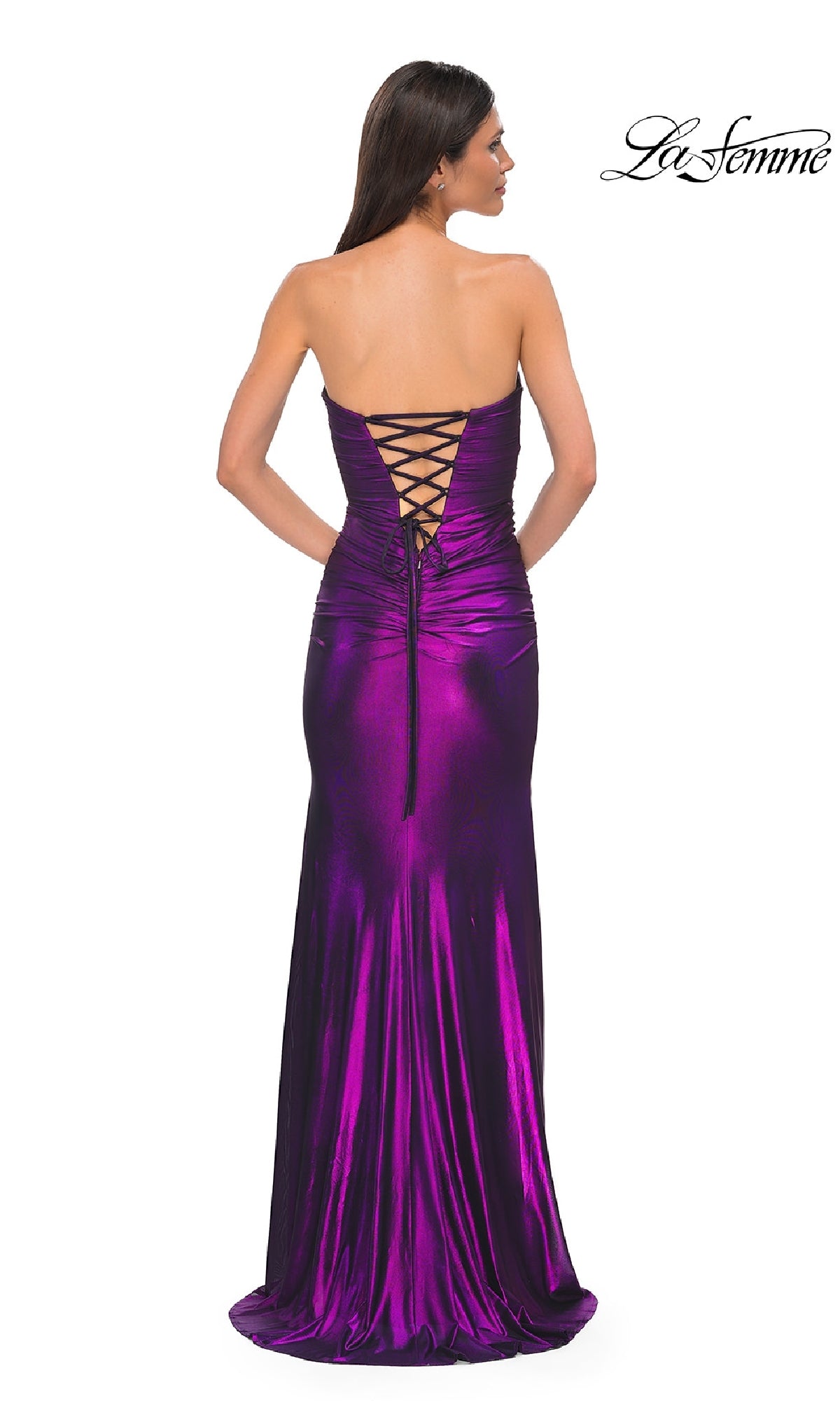 A woman wearing the Cut-Out Strapless Long Prom Gown, La Femme 32987, with a lace-up back stands facing away. The metallic fabric shimmers, making a statement as the La Femme logo appears in the top right corner.