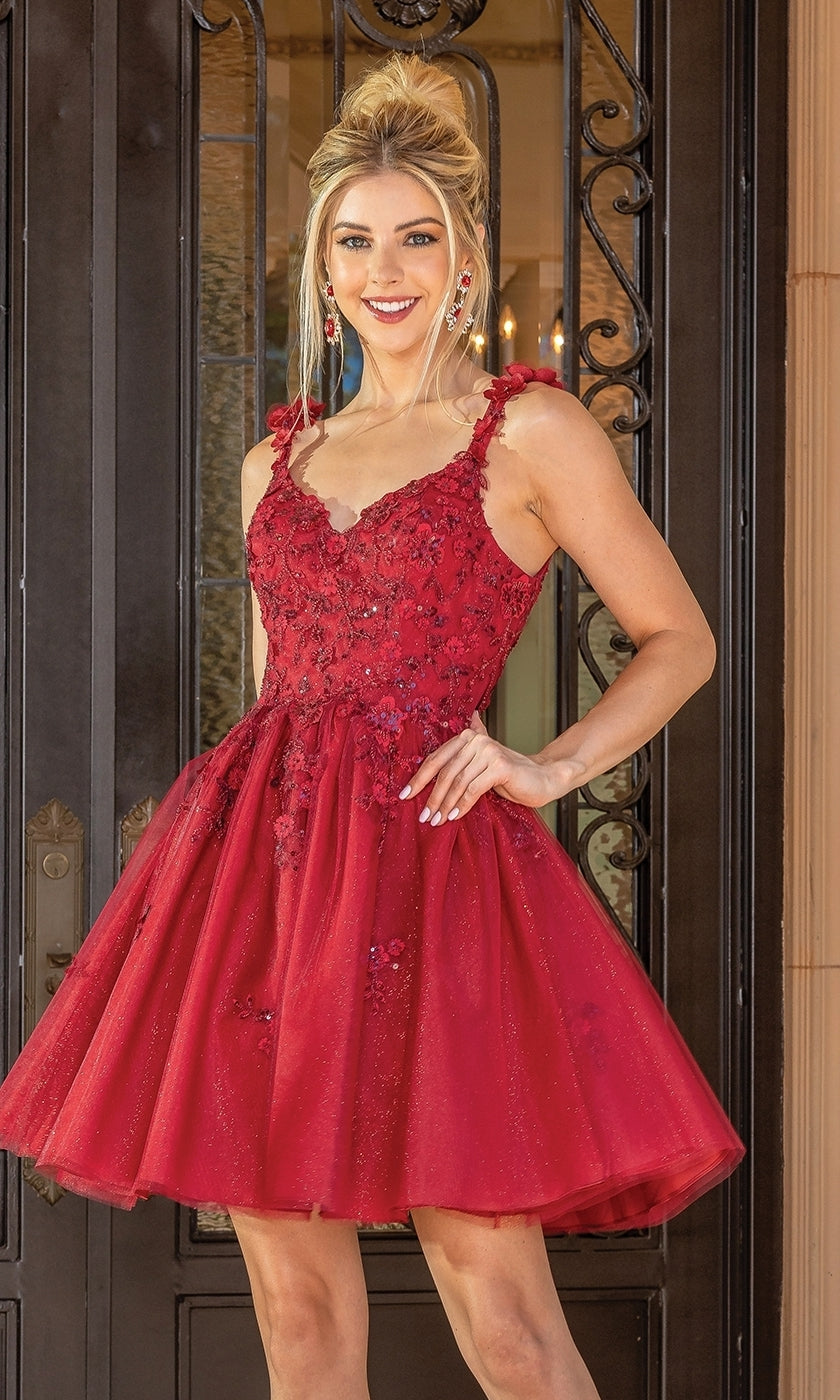 A woman in a sleeveless Floral Applique Short Babydoll Glitter Hoco Dress poses, smiling with one hand on her hip, in front of ornate black doors.