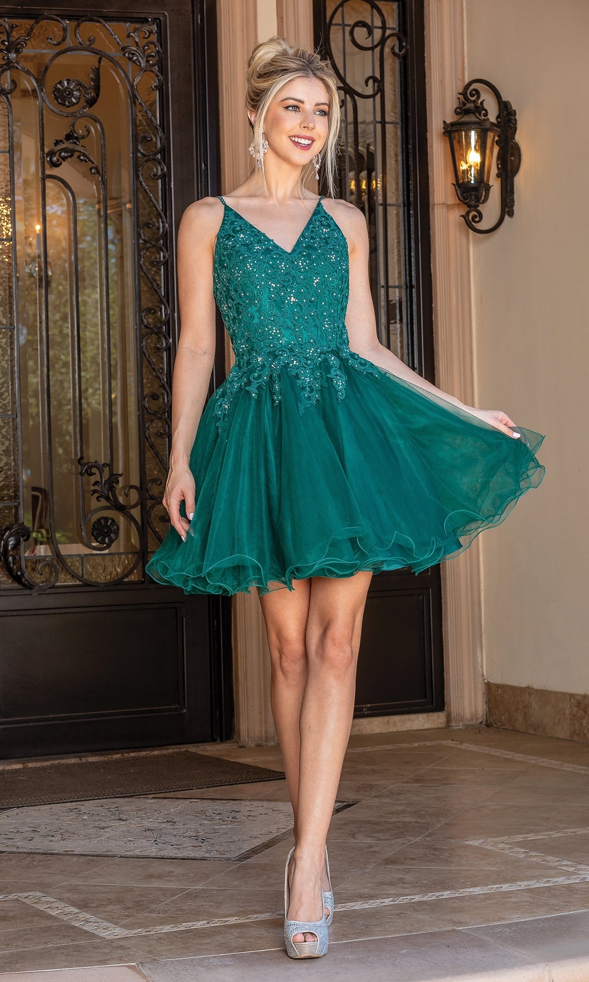 A woman stands at an entrance wearing the Lace-Up Short Babydoll Homecoming Dress 3303 in green, featuring a sleeveless A-line silhouette, beaded corset bodice, and paired with silver high heels.