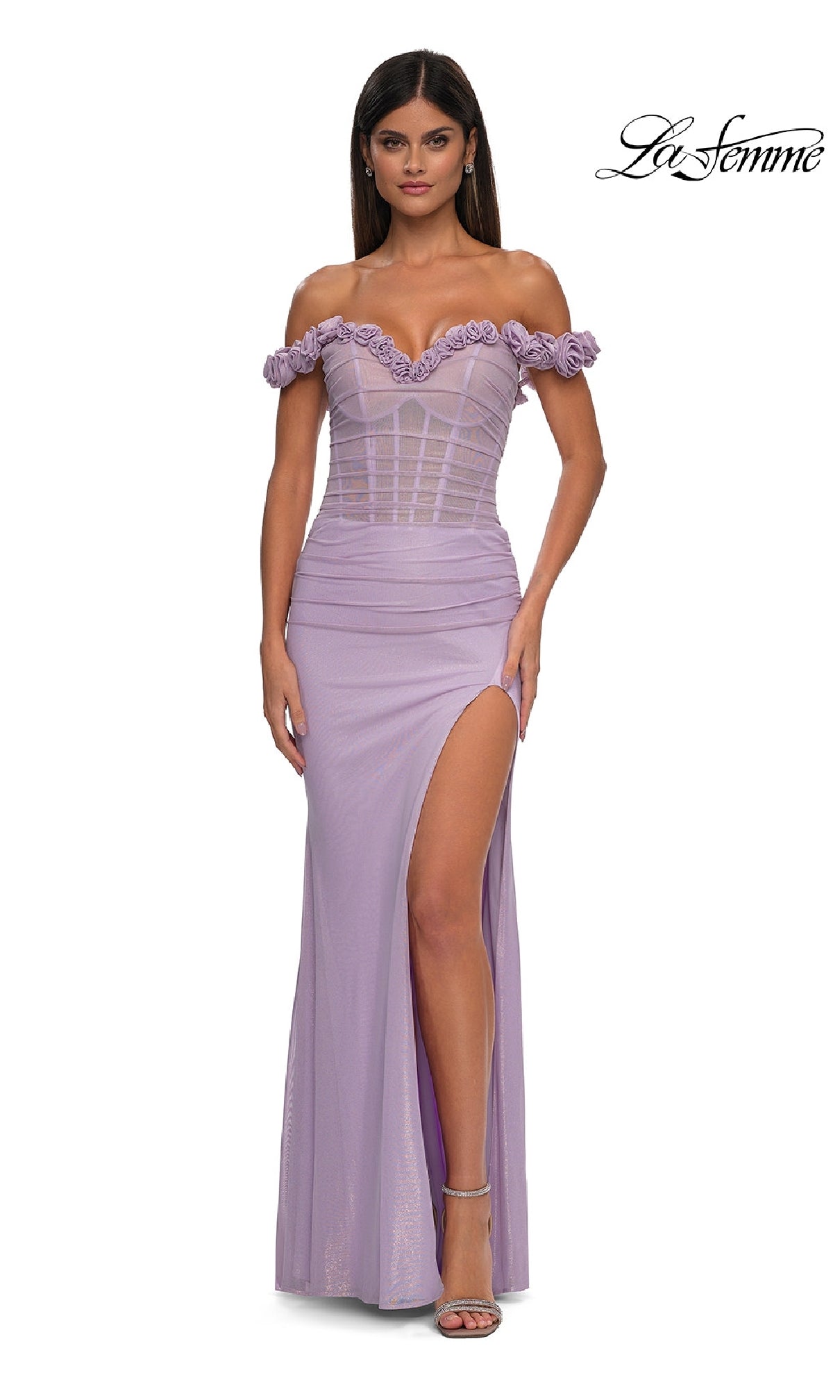 A woman wears the Sheer-Corset Long Prom Dress, La Femme 33004—a lavender off-the-shoulder gown with a fitted bodice, floral trim, sheer panels, and a high side slit. The La Femme logo is in the top right corner.