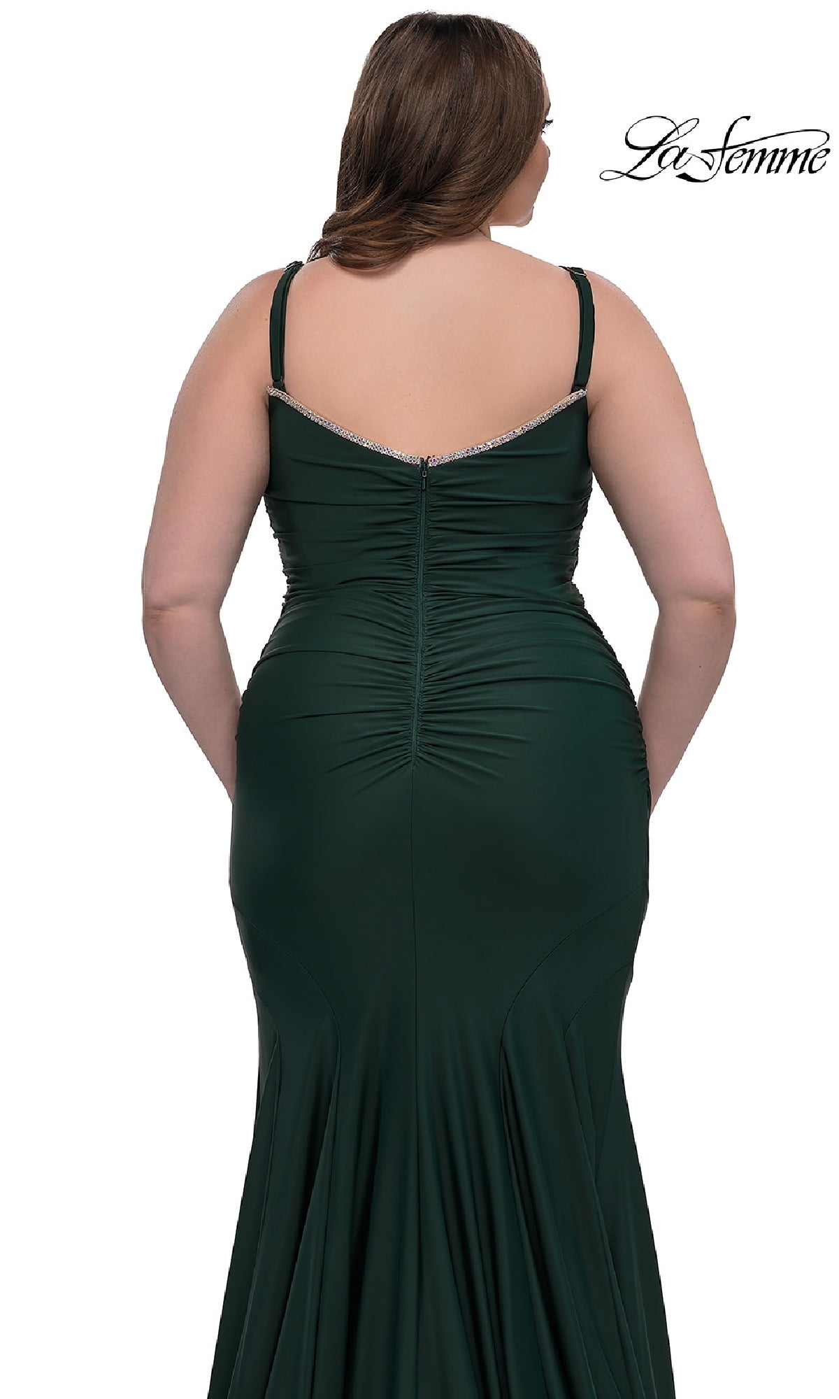 A woman in a dark green, fitted Plus-Size Floor-Length Prom Dress (La Femme 33057) with thin straps and back ruching is shown from behind on a white background. The La Femme logo appears in the top right corner.