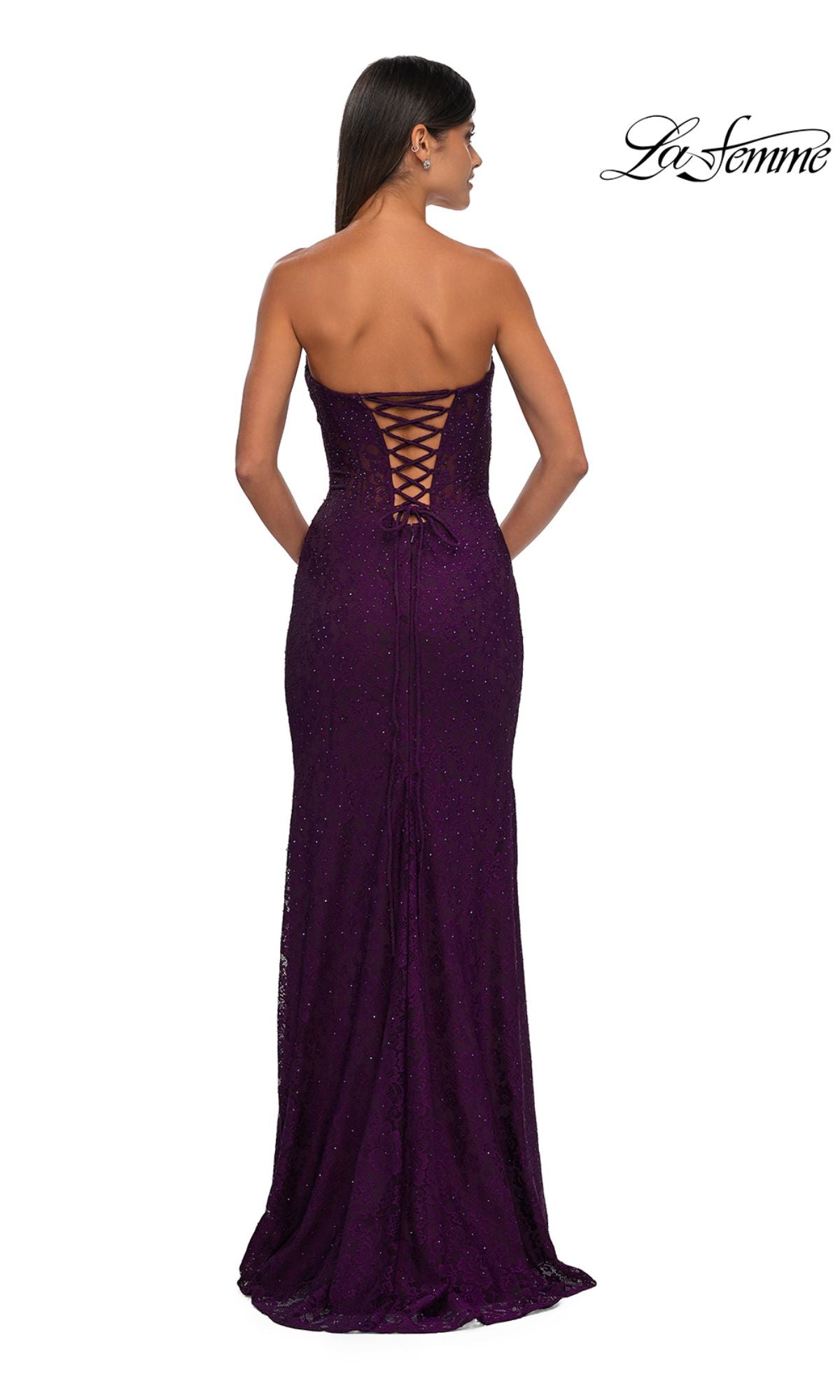 A woman stands with her back to the camera, wearing the La Femme 33069 strapless long lace prom dress, floor-length in deep purple with a lace-up back detail.