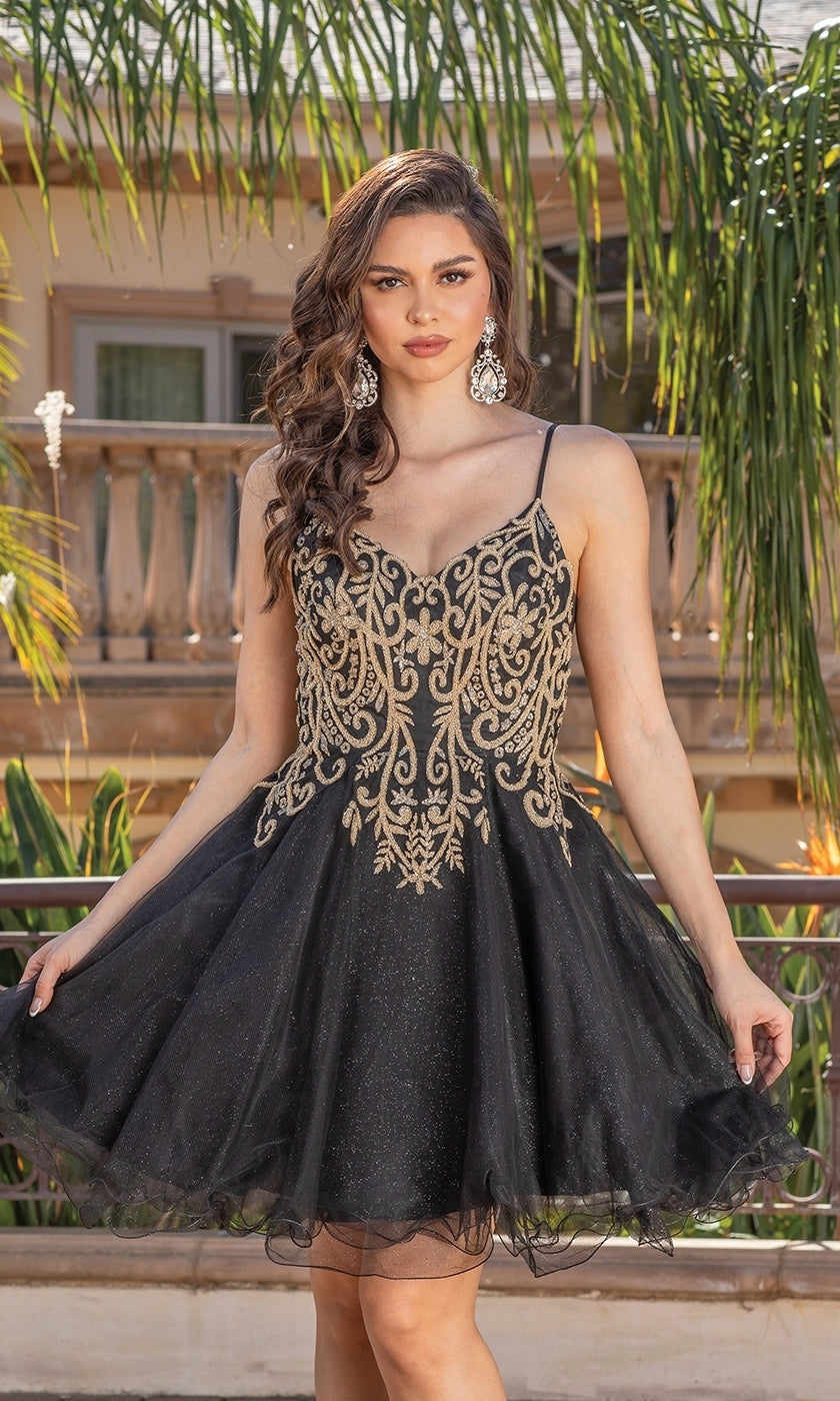 A woman stands outdoors by a balcony and palm trees, holding out the skirt of the Gold-Embroidered Short Homecoming Dress 3330, a sleeveless black party dress with gold embroidery.