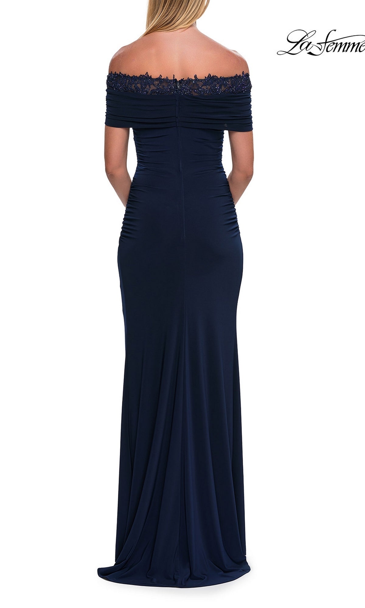 A woman is seen from the back wearing the La Femme 33329 Lace-Trimmed Tight Long Prom Dress in navy blue, which features an off-the-shoulder design and lace trim.