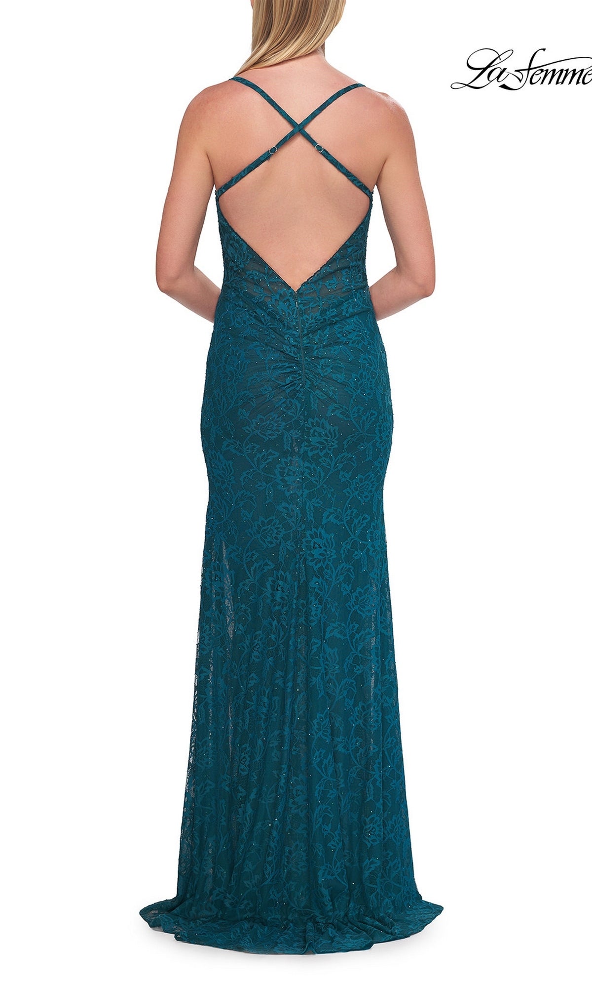 A woman stands facing away from the camera, wearing the La Femme 33381 long prom dress—an elegant floor-length teal lace gown featuring a fitted silhouette, open back, and crisscross straps.