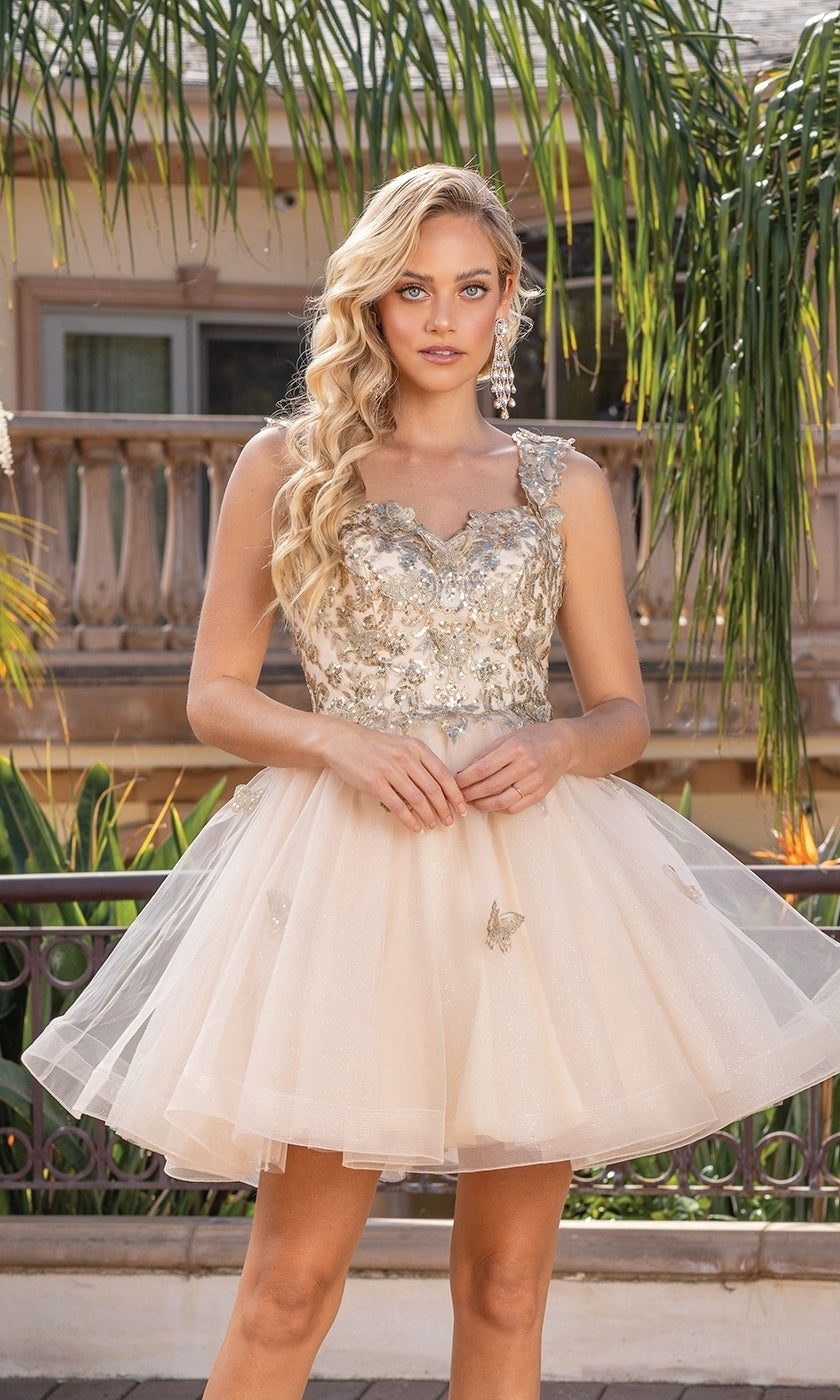A woman stands outdoors in front of lush greenery and a building, wearing the Embroidered-Lace Short Babydoll Hoco Dress 3338 with silver embellishments.