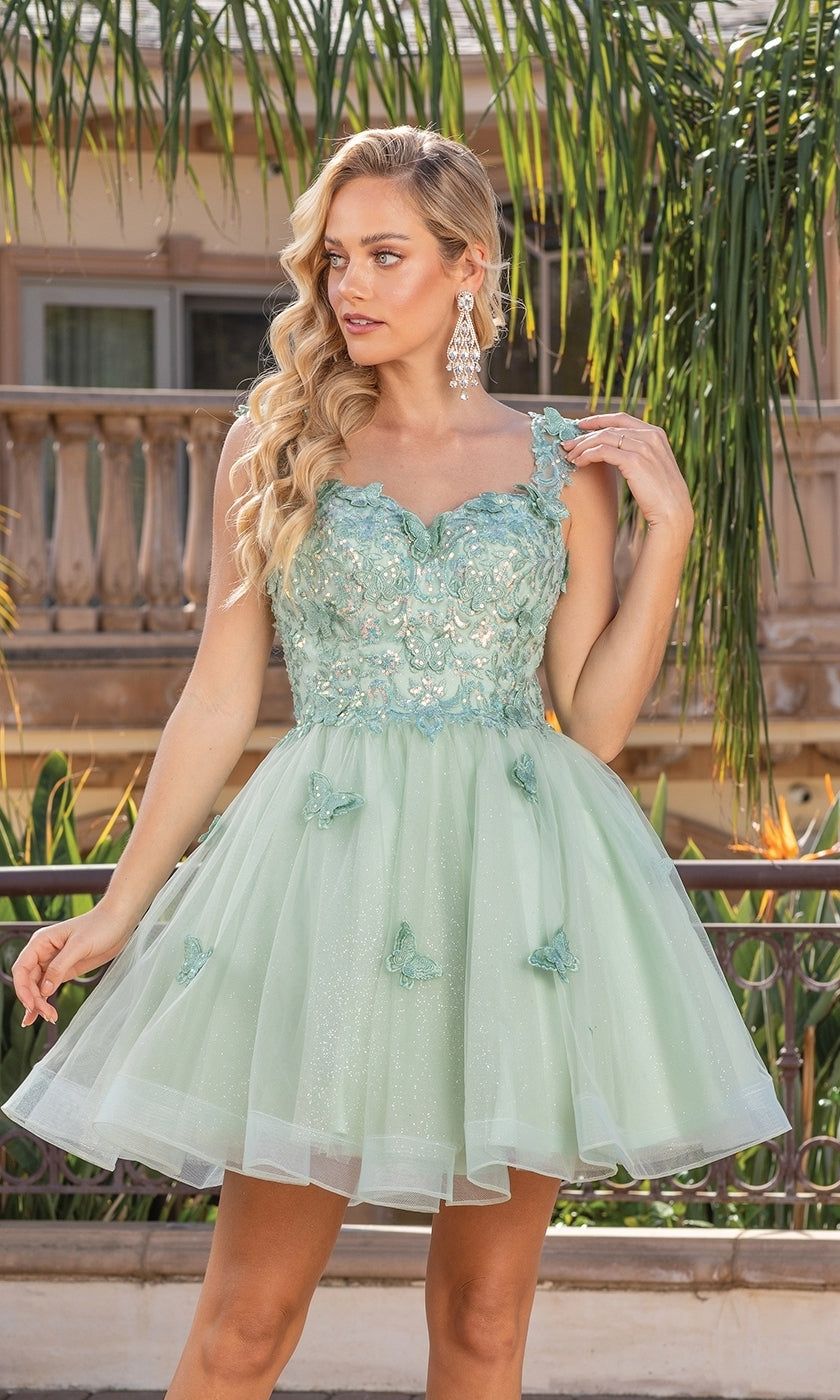 A woman stands outdoors near greenery and a building, showcasing the Embroidered-Lace Short Babydoll Hoco Dress 3338—a light green, semi-formal dress with delicate embroidery and a flared skirt.