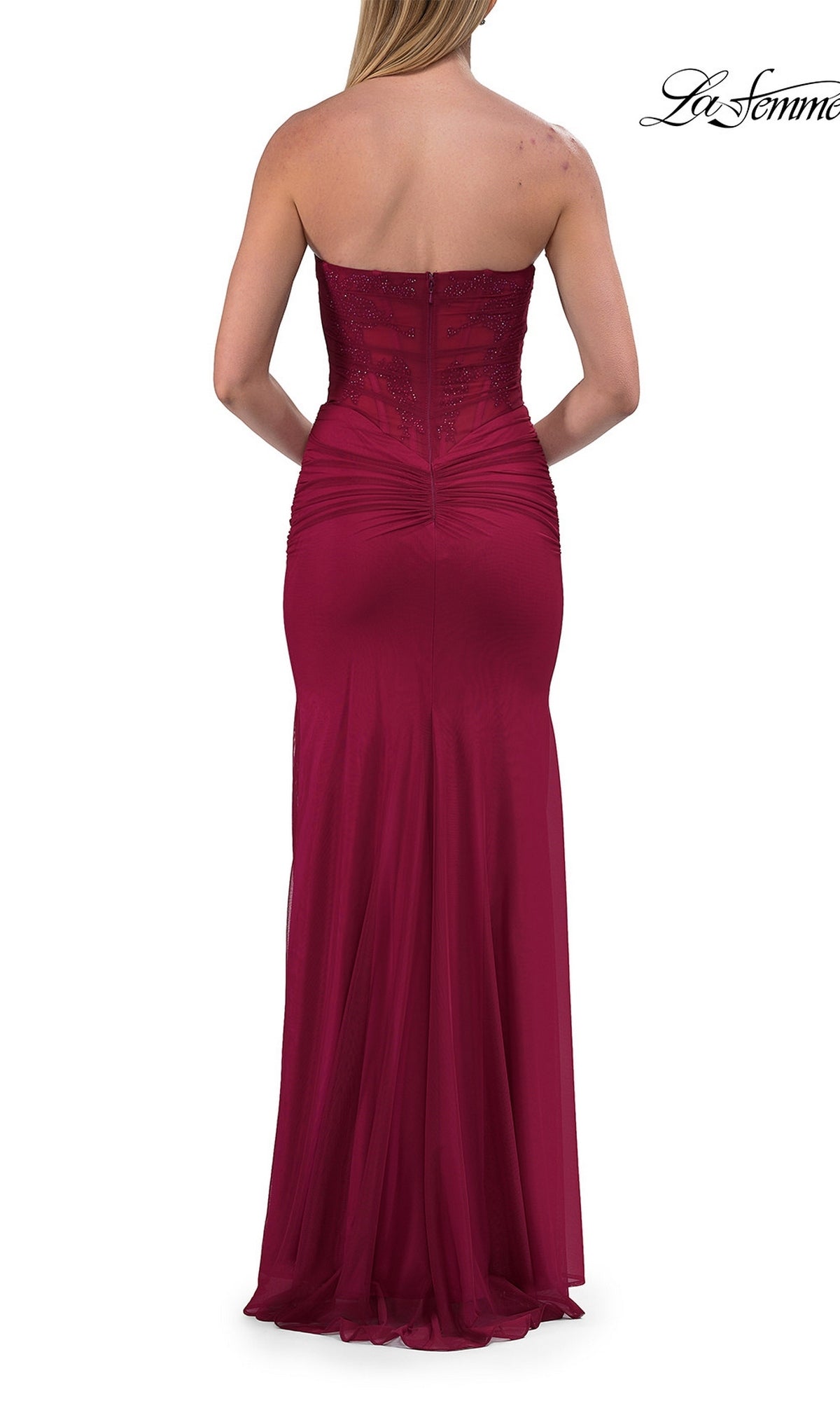 A woman is shown from the back wearing the La Femme 33465, a simple strapless long prom dress in maroon with elegant ruching and subtle embellishments.