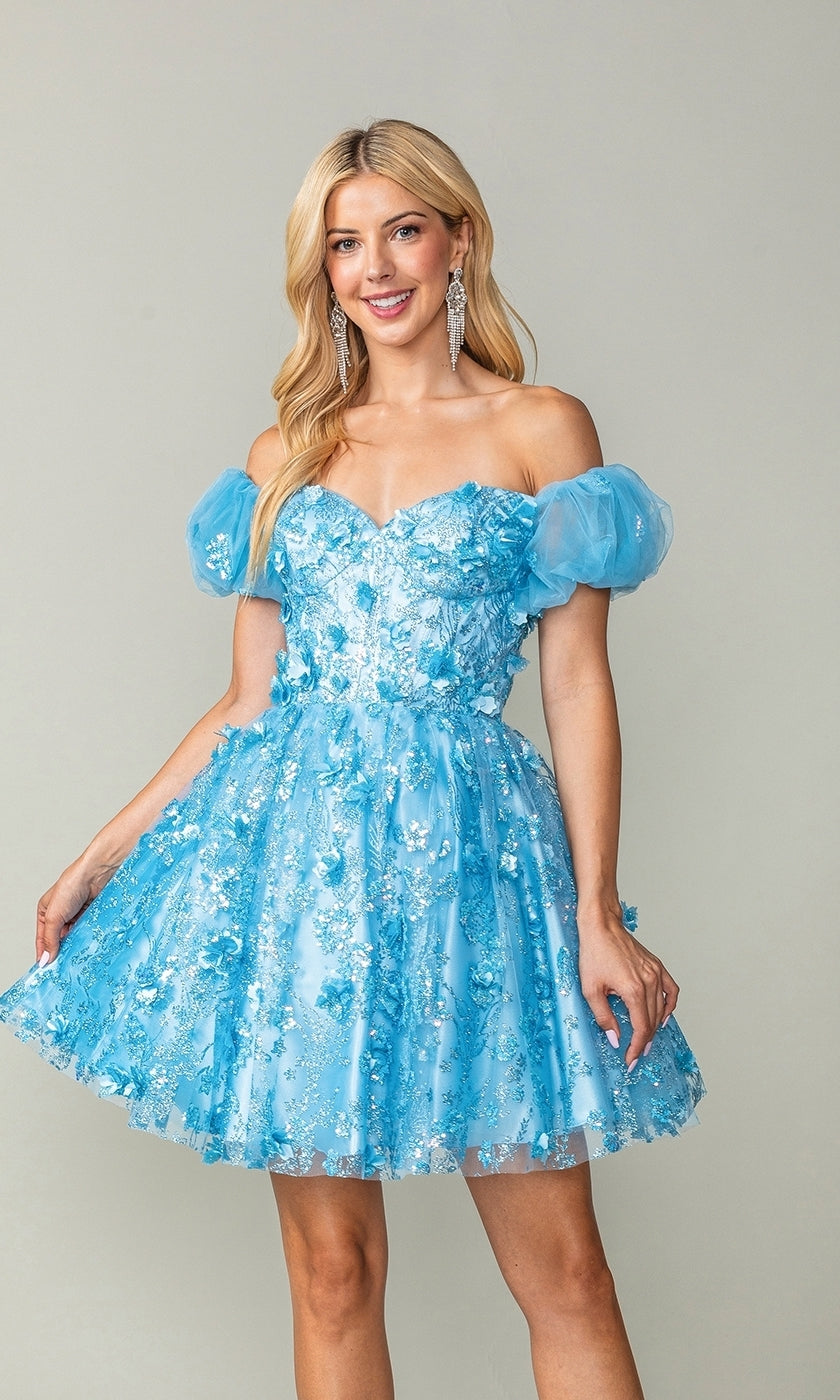A woman wears the Short Sleeve Short Glitter Homecoming Dress 3355, a light blue dress with puff sleeves and floral embellishments, styled for homecoming against a plain light background.