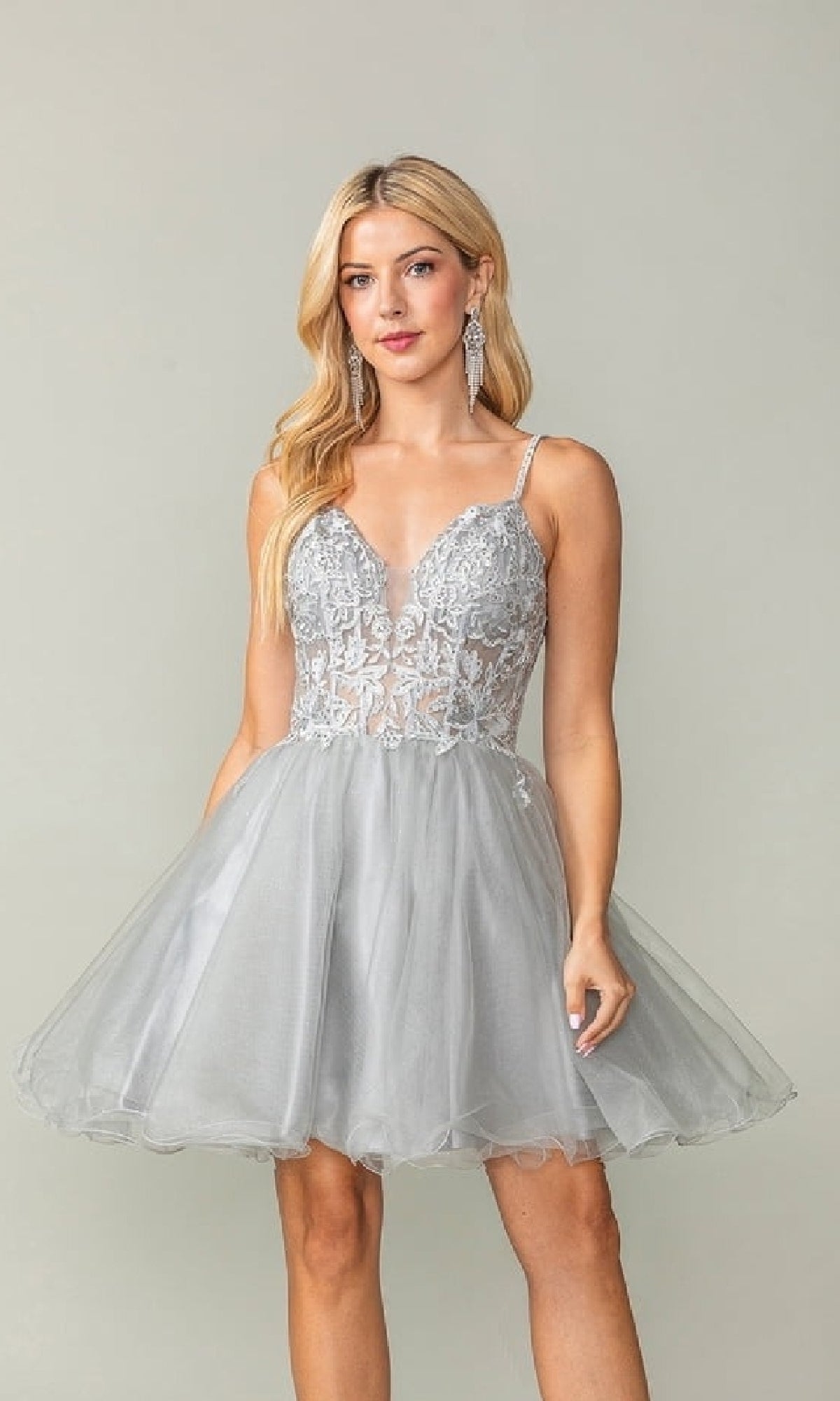 Woman wearing a silver short dress with a lace bodice and flared tulle skirt, against a plain background