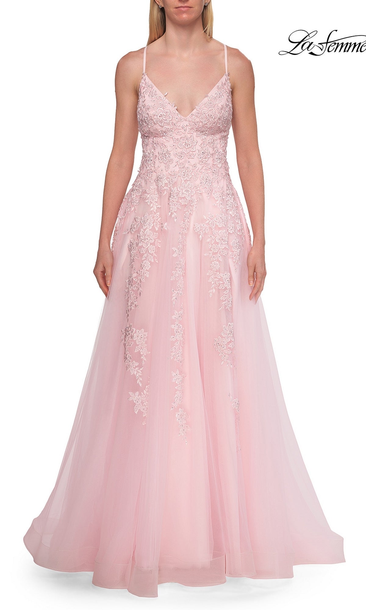 A woman is wearing the Floral Lace Embroidered Prom Dress: La Femme 33715, a floor-length, light pink gown featuring floral lace appliqué details, thin straps, and a fitted bodice. The image has a white background with the La Femme logo in the top right corner.