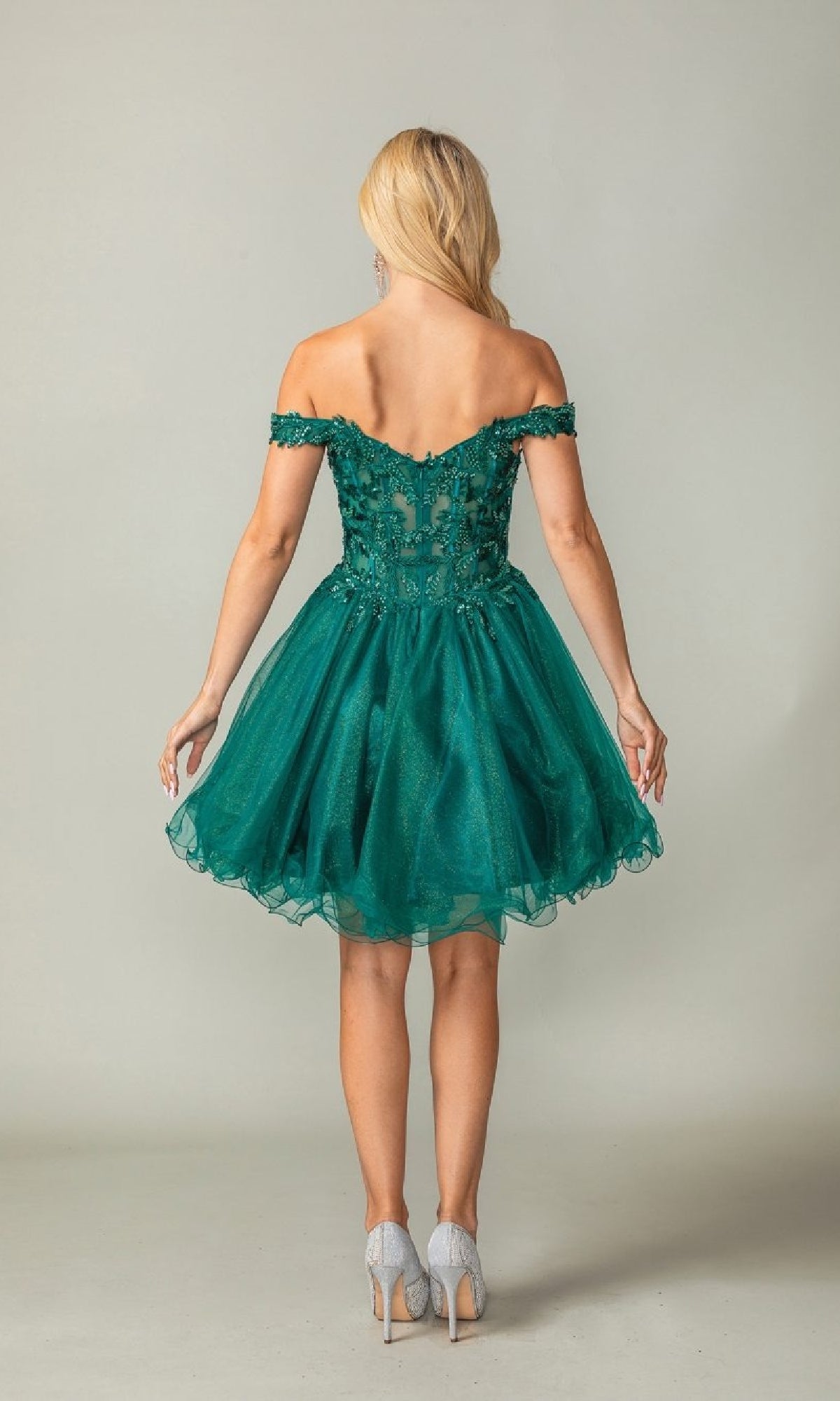 Woman wearing a green off-shoulder short dress against a plain background