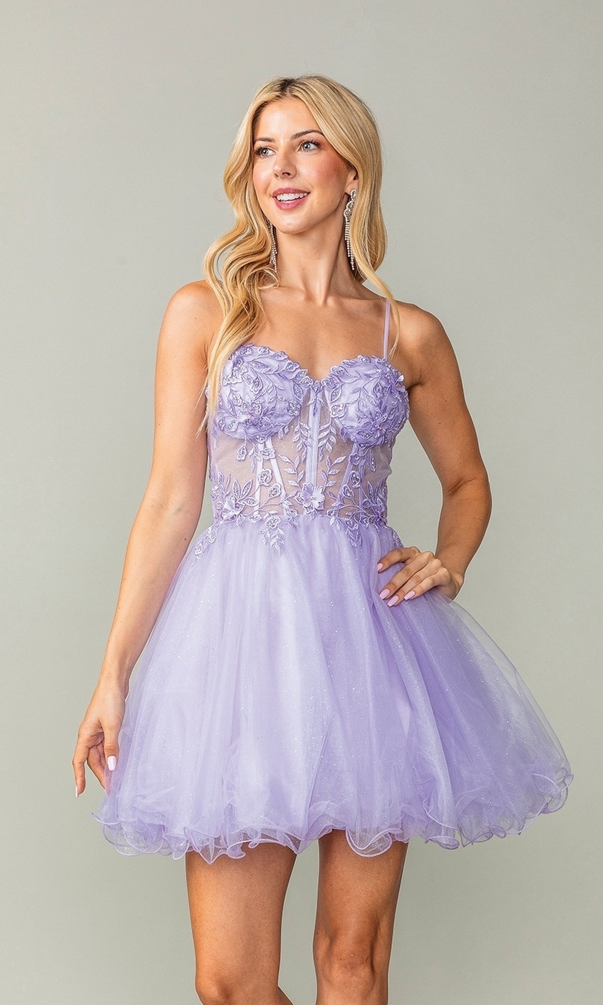 Woman wearing the Sheer-Waist Short Babydoll Homecoming Dress 3382—a light purple dress with a corset-style bodice, floral lace accents, and a tulle skirt—standing against a plain light background.