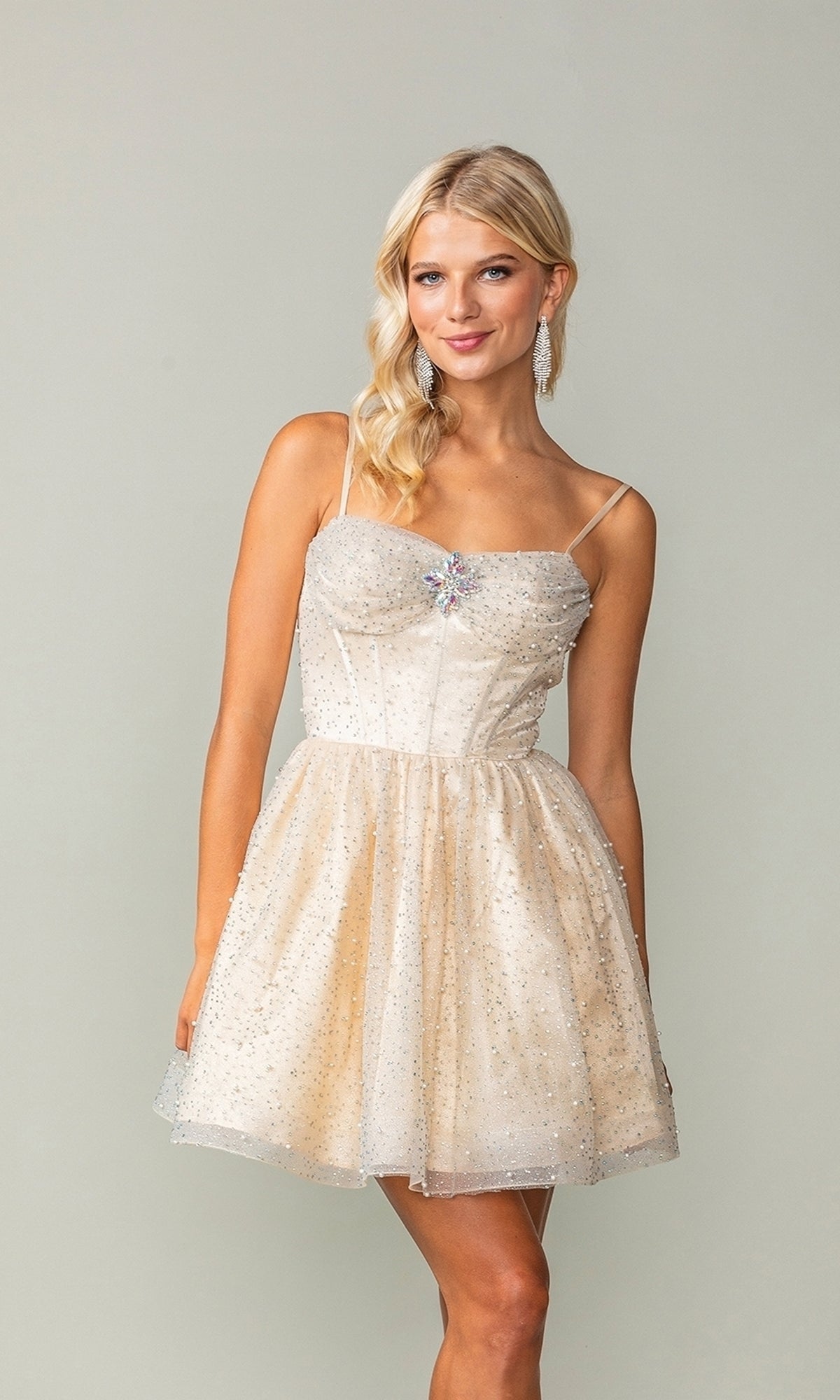 A woman models the Short Glitter Fit-and-Flare Homecoming Dress 3389, featuring thin straps and sparkly embellishments, standing against a plain background to showcase this elegant semi-formal dress.