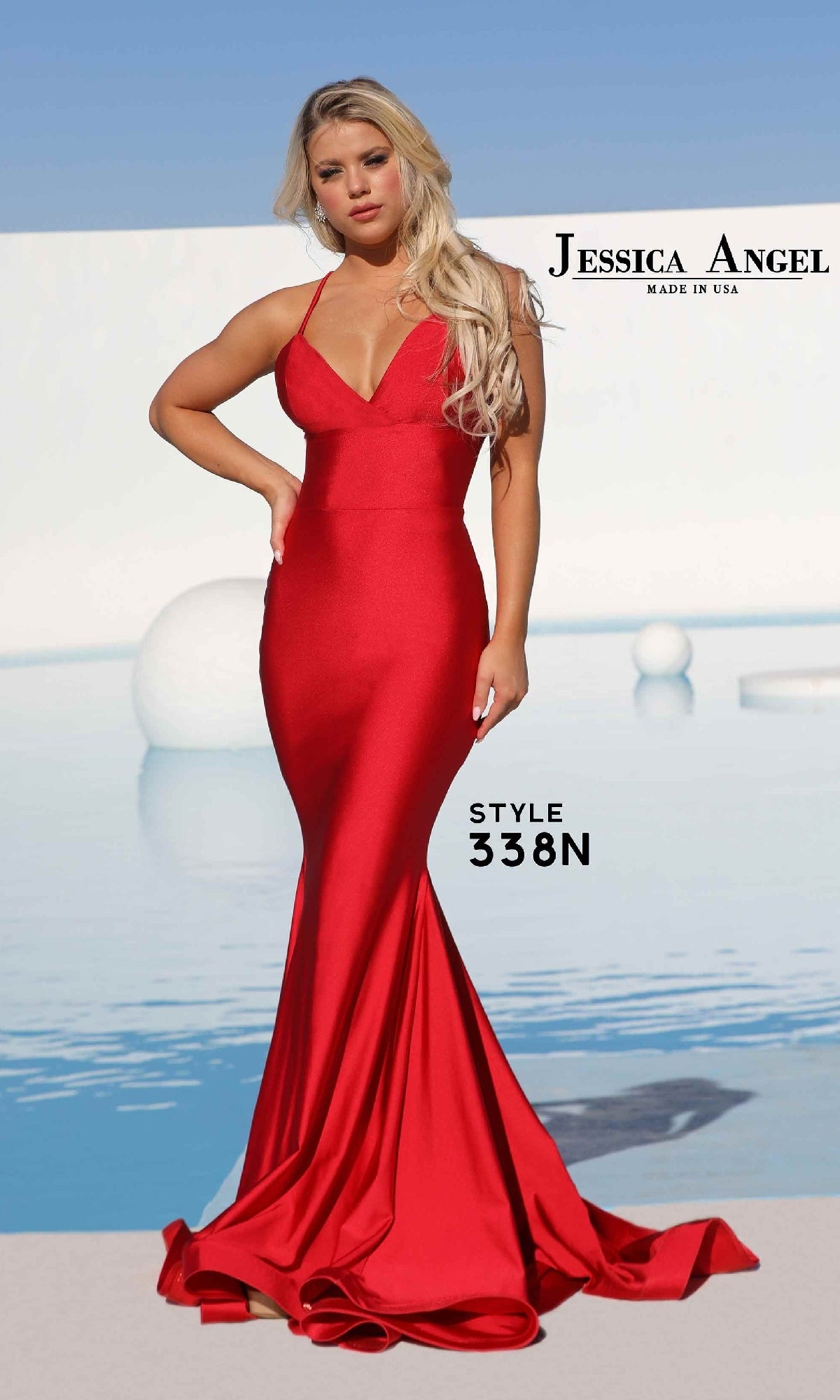 A woman stands by a pool under clear blue skies wearing the Strappy-Back Long Prom Dress: Jessica Angel 338N, a fitted, floor-length red mermaid gown.