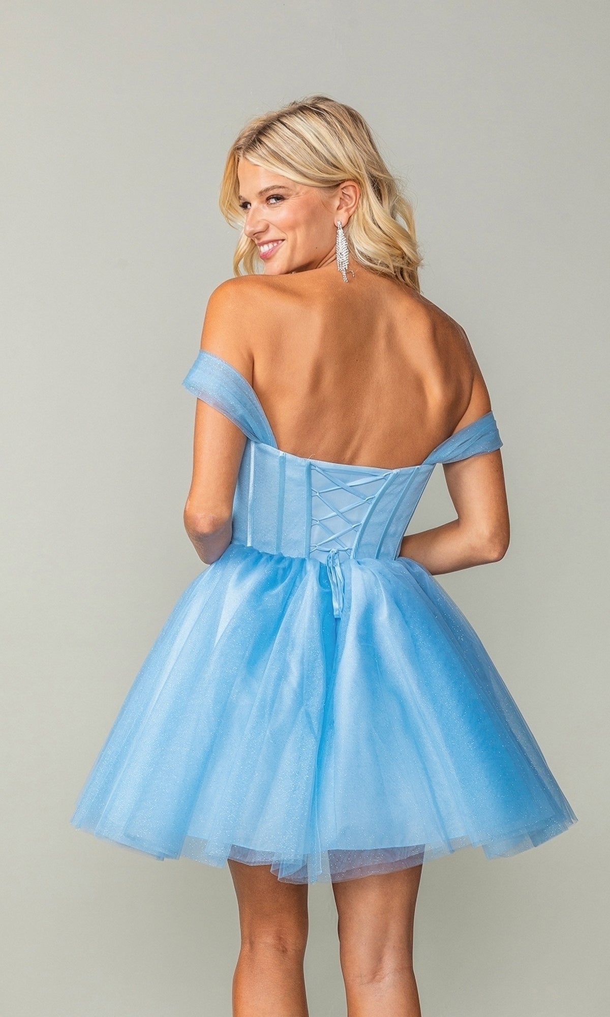 A woman poses with her back to the camera, wearing the Off-Shoulder Short Fit-and-Flare Hoco Dress 3394 in light blue, featuring a corset-style bodice and a tulle skirt against a plain background.