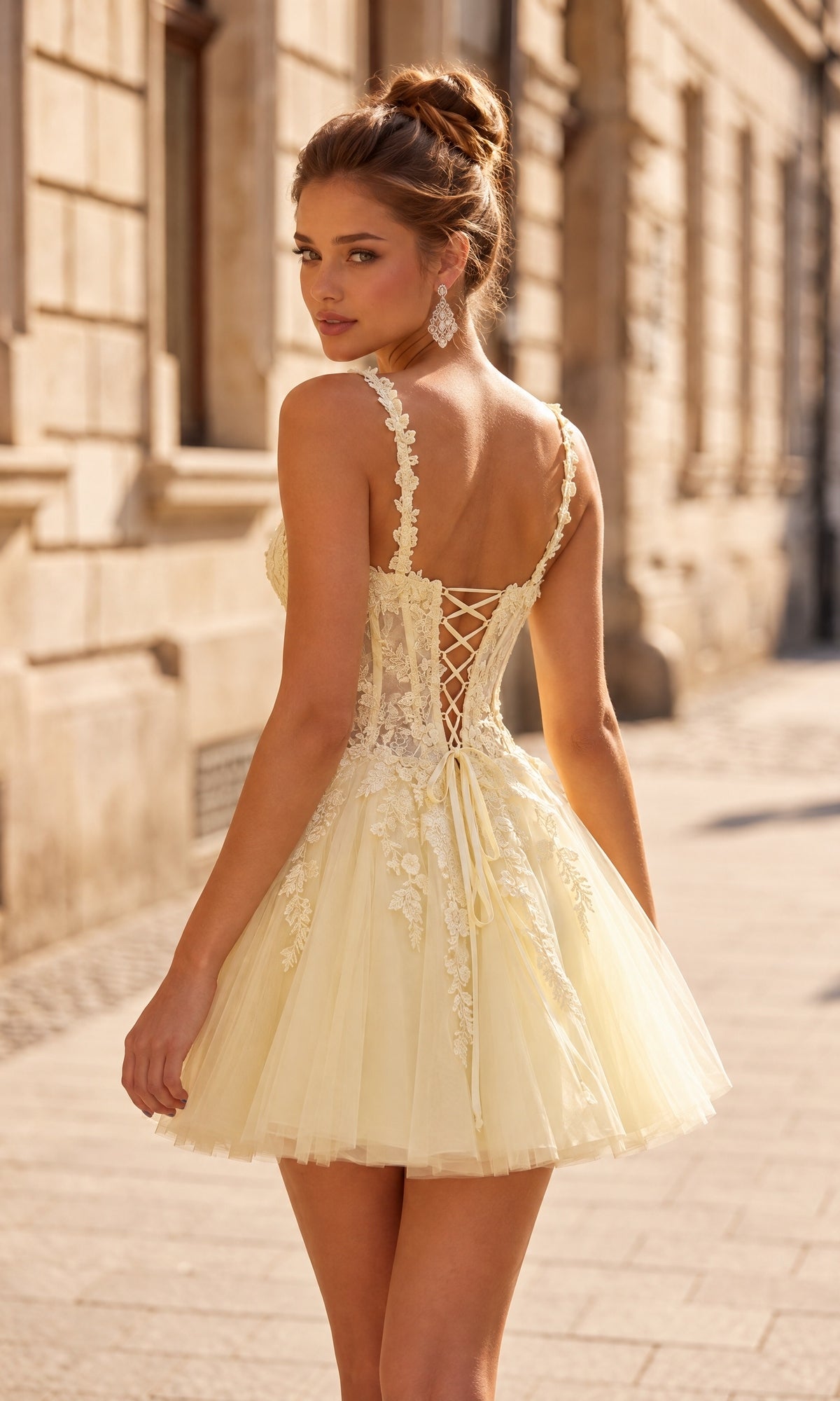 Wearing the La Femme 34146 short homecoming dress, a woman stands on a city street looking over her shoulder. The light yellow lace dress features elegant embroidery, floral details, and a corset back with a flattering fit-and-flare silhouette—making it the perfect choice for a cute homecoming look.