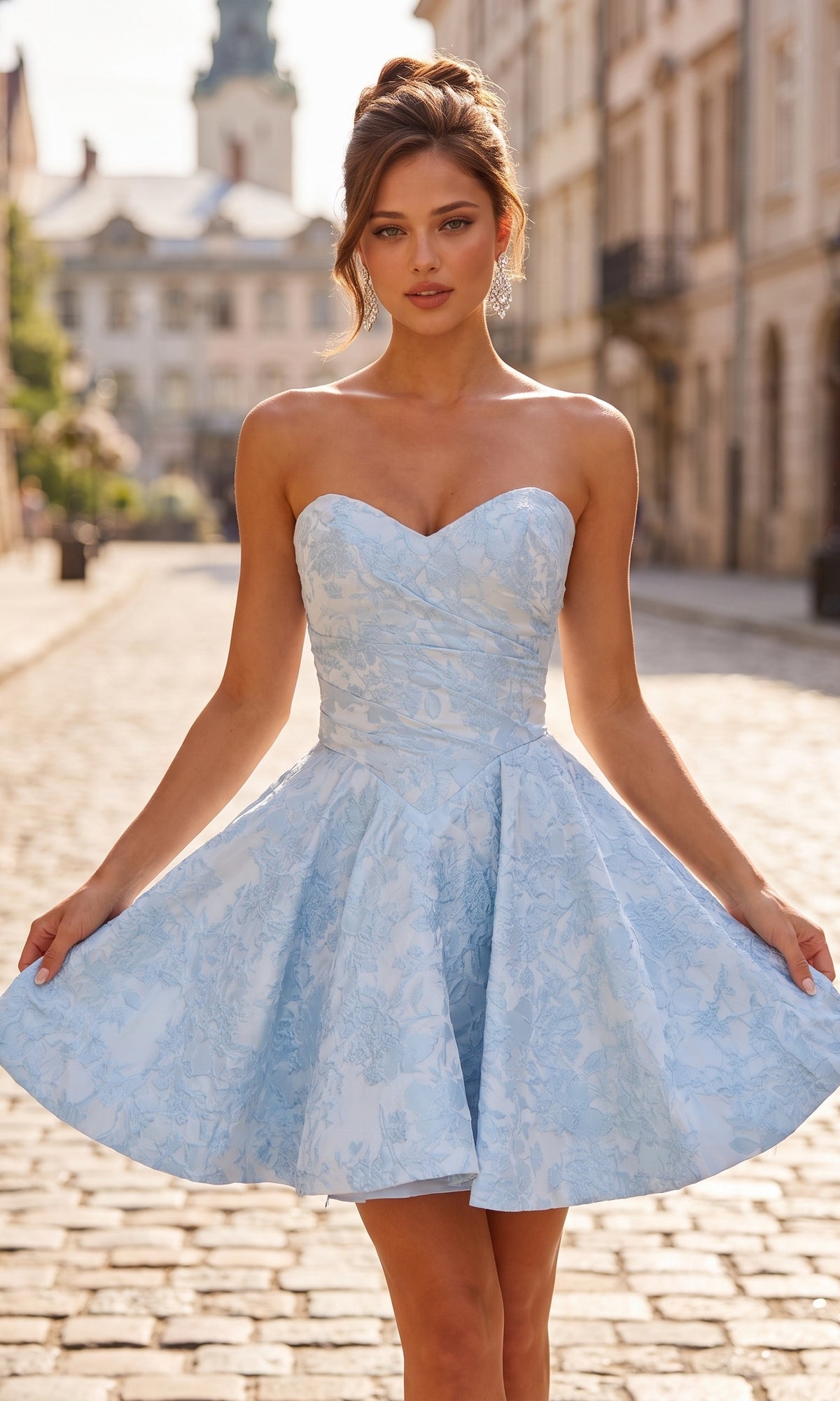 A woman wears the La Femme 34147 Strapless Mini Floral Hoco Dress in light blue as she stands on a cobblestone city street, with buildings and a tower visible in the background.