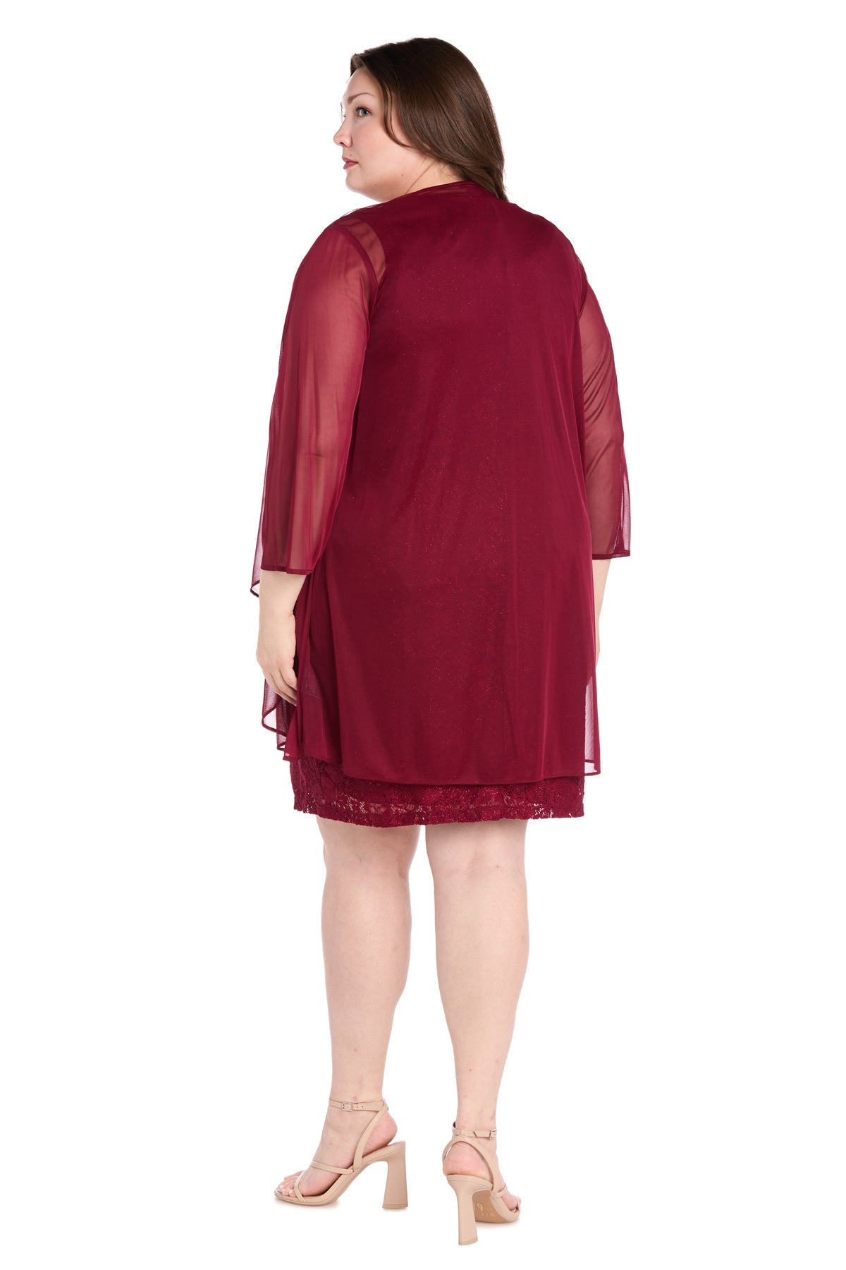A woman stands with her back to the camera against a white backdrop, modeling the R&M Richards 3594W Plus-Size Short Jacket Dress, a knee-length burgundy cocktail outfit with sheer sleeves and nude heels.